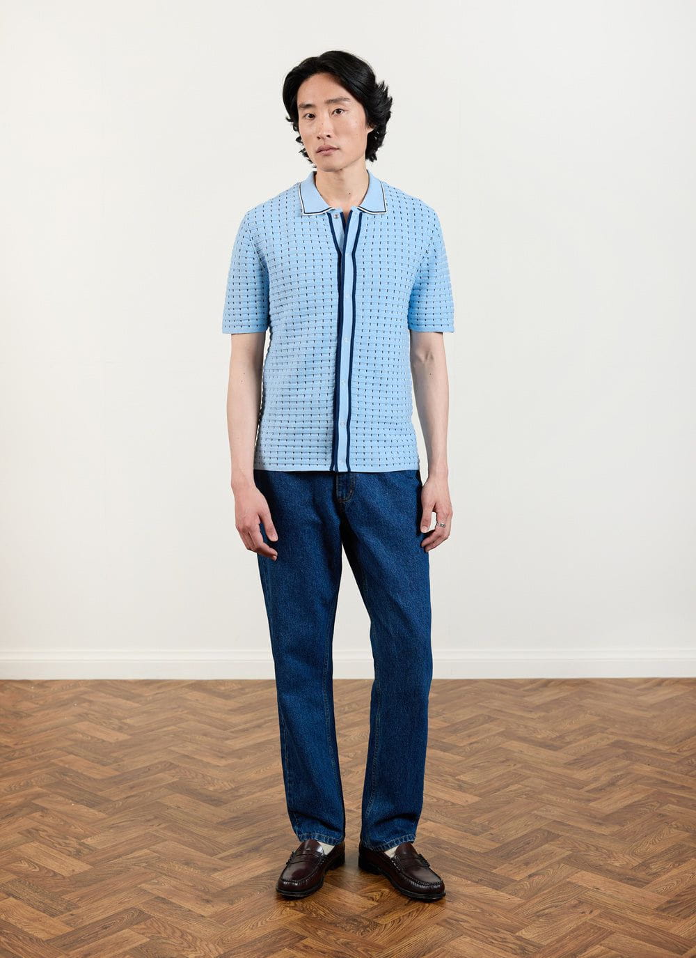 The Percival Broken Stripe Knitted Shirt in blue, a short-sleeve knit shown full-length on a model with dark wash jeans.