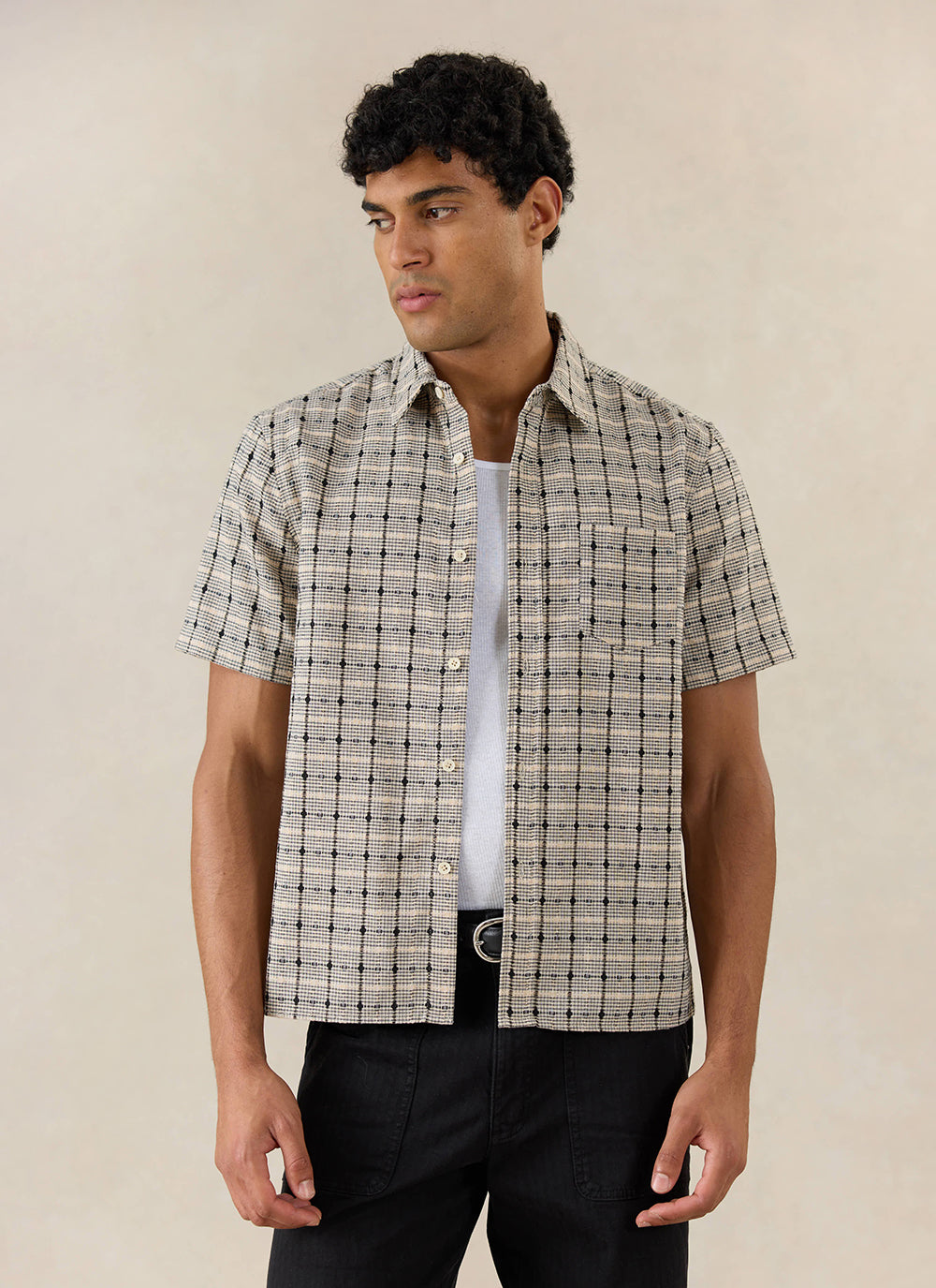 Model wears the Percival Bayley Textured Check Shirt in cream cotton, styled over a white tank top and black trousers.