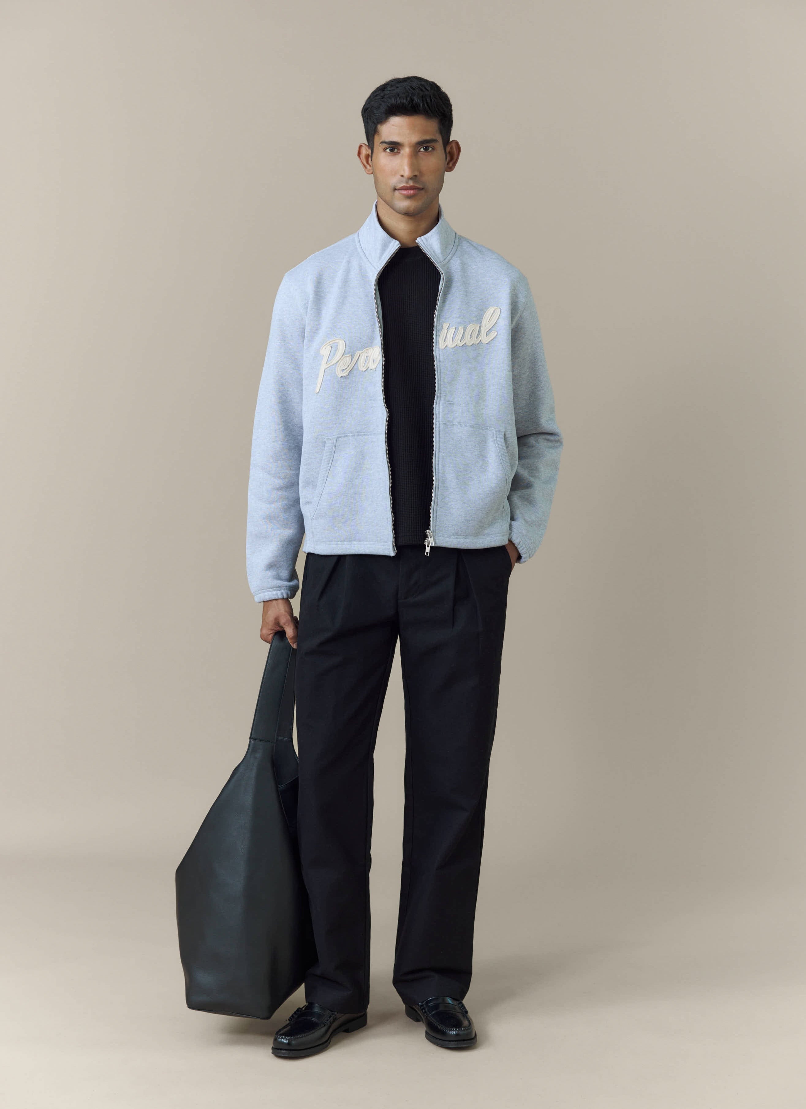 A model wears the Percival Curtis Boxy Zip Funnel Neck Sweatshirt in athletic grey, styled over a black top and trousers.