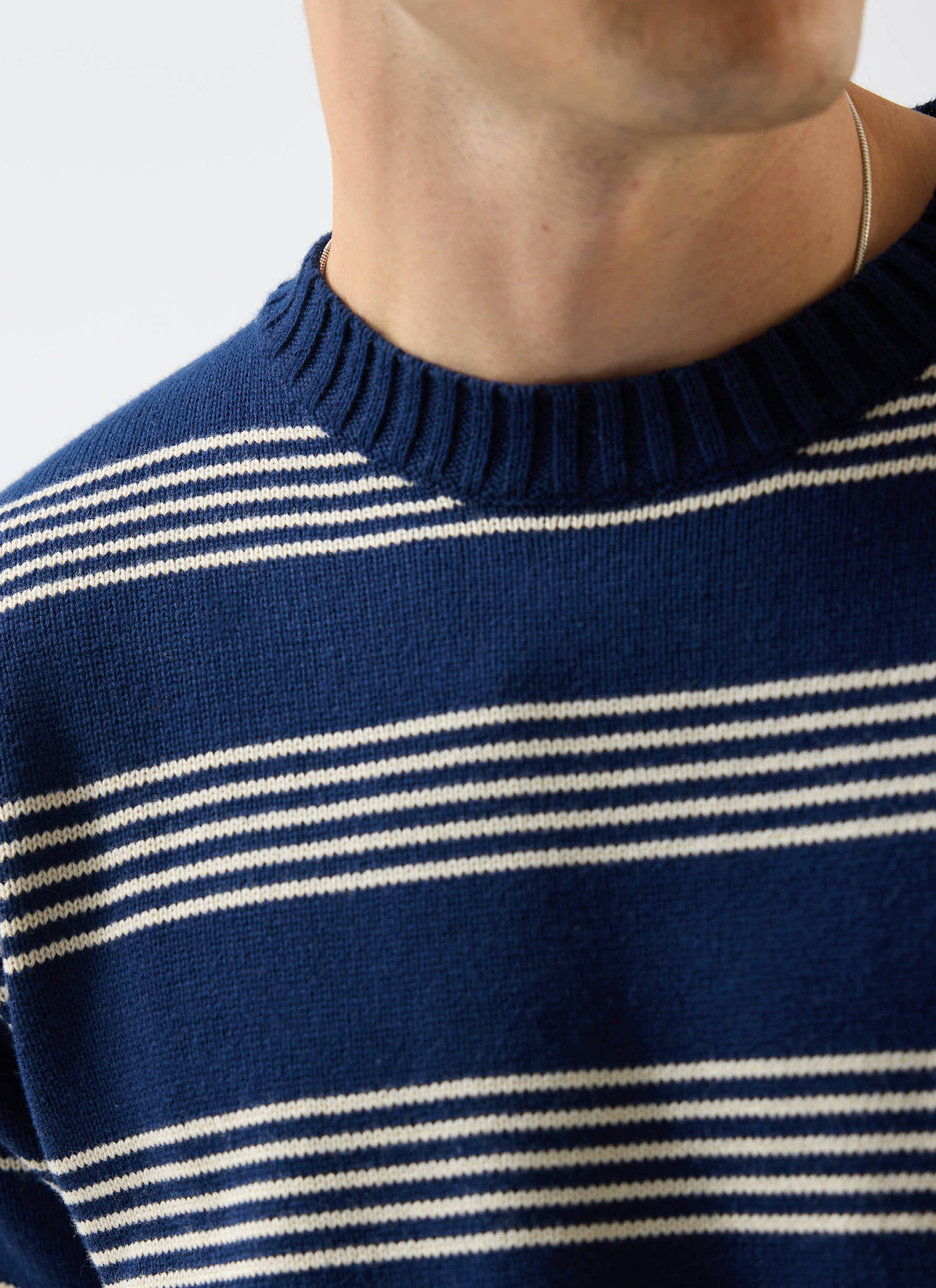 A close-up of a model wearing the Percival Fiction Striped Knitted T Shirt in navy, showing the ribbed collar detail.