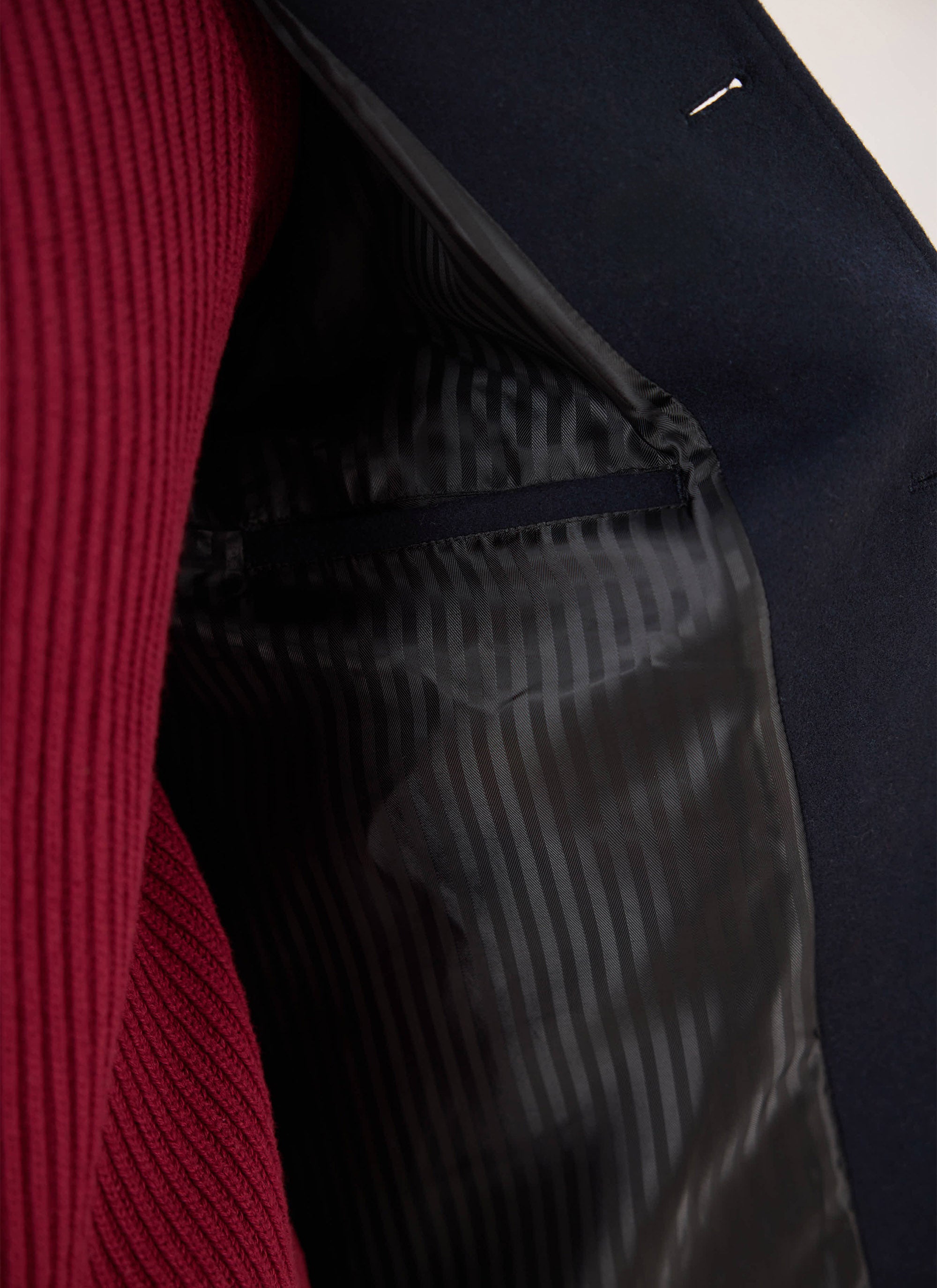 Close-up of the tonal jacquard lining and internal welt pocket inside the navy wool Percival peacoat.