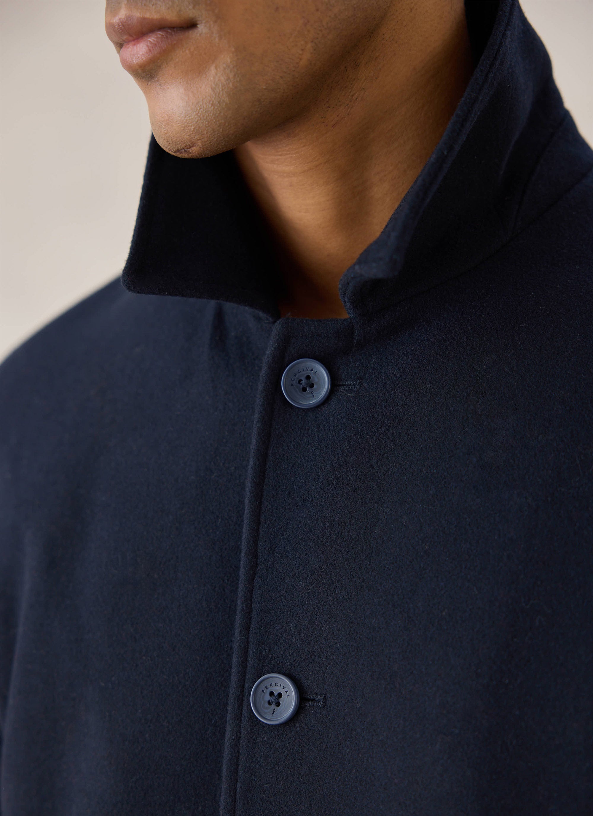 Close-up of a model wearing a navy blue Percival melton wool peacoat, highlighting the collar and buttons.