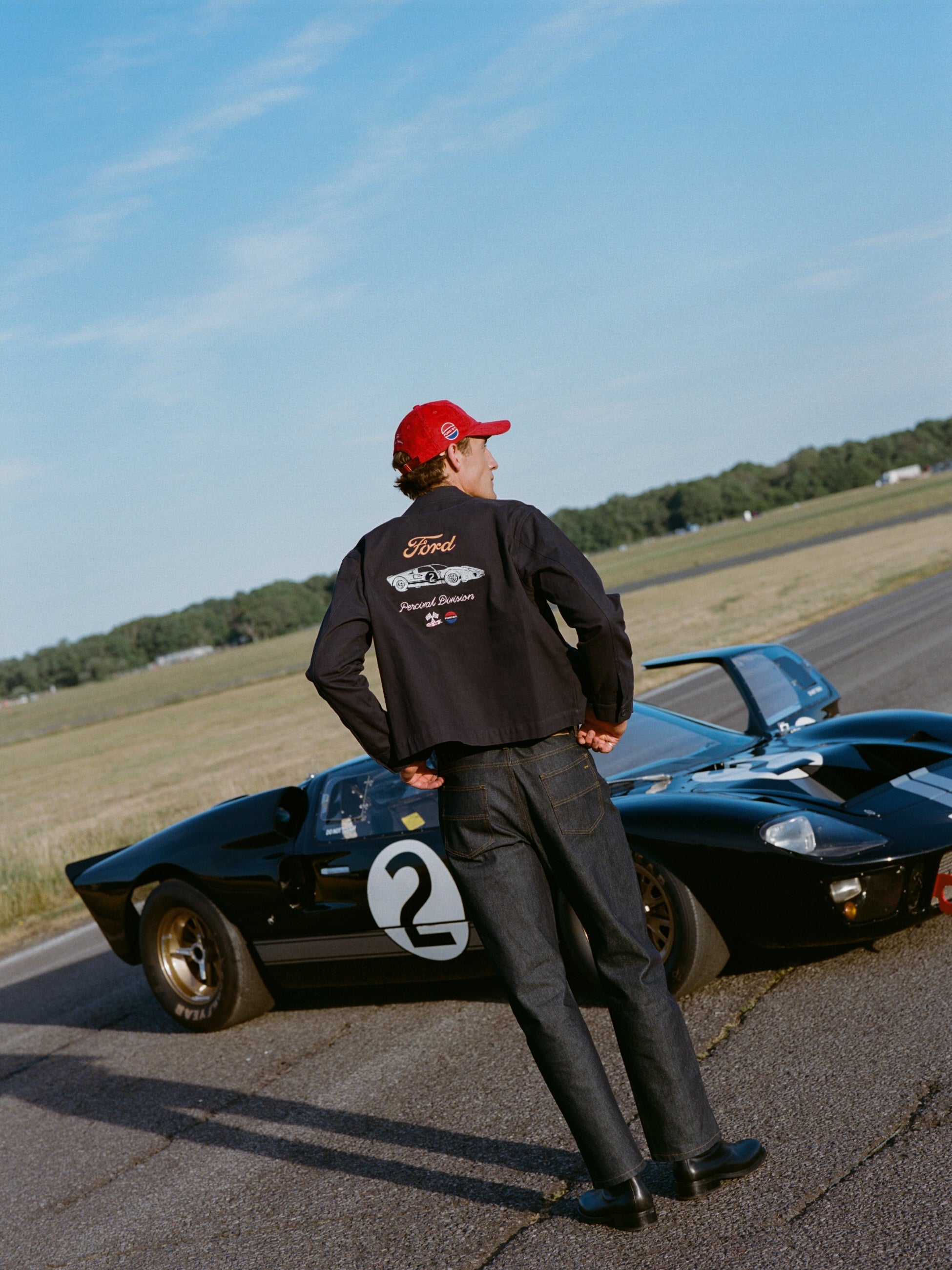 Navy Percival x Ford GT40 canvas jacket with back embroidery, styled with heritage denim jeans beside a classic GT40.