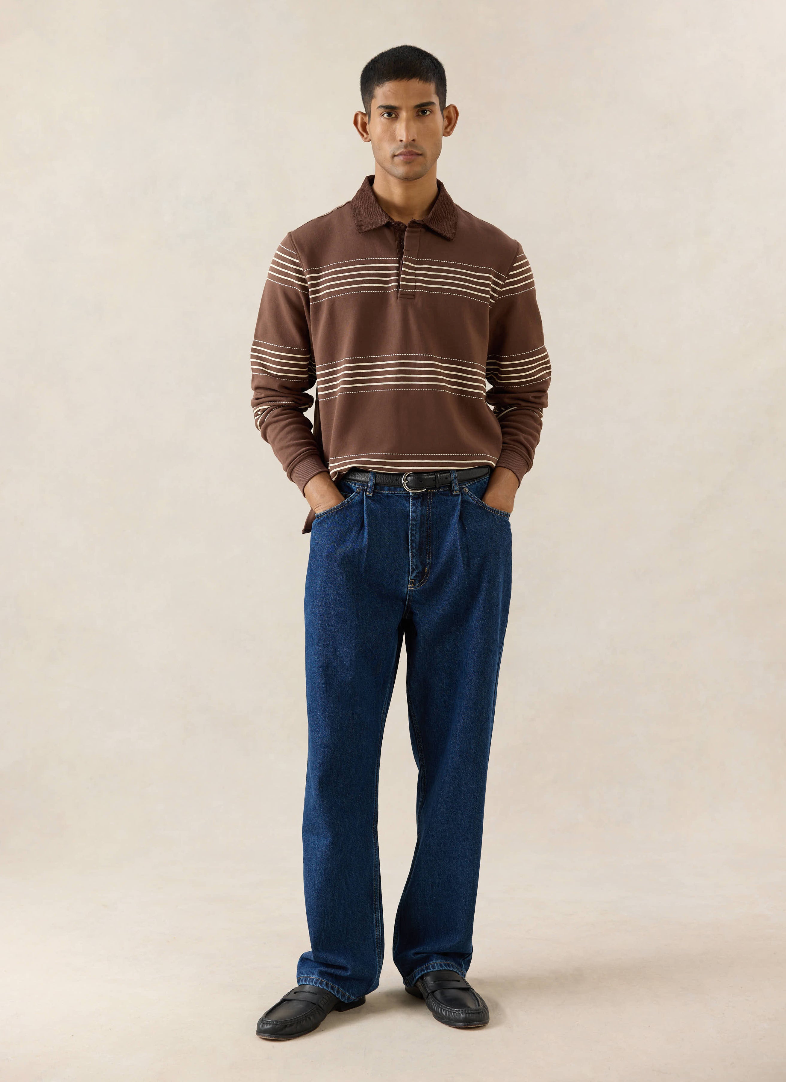 Percival mid wash blue 12oz cotton pleated denim jeans, paired with a brown Editor rugby polo and black loafers.