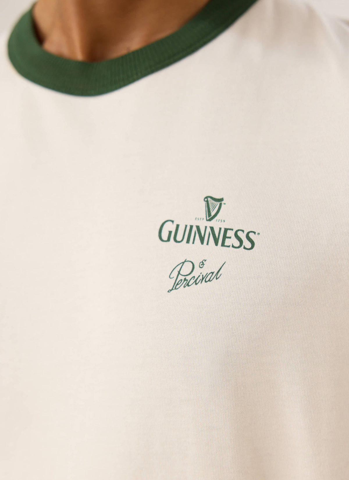 Close-up of the Guinness x Percival cream ringer T-shirt, showing the green contrast collar and chest print.