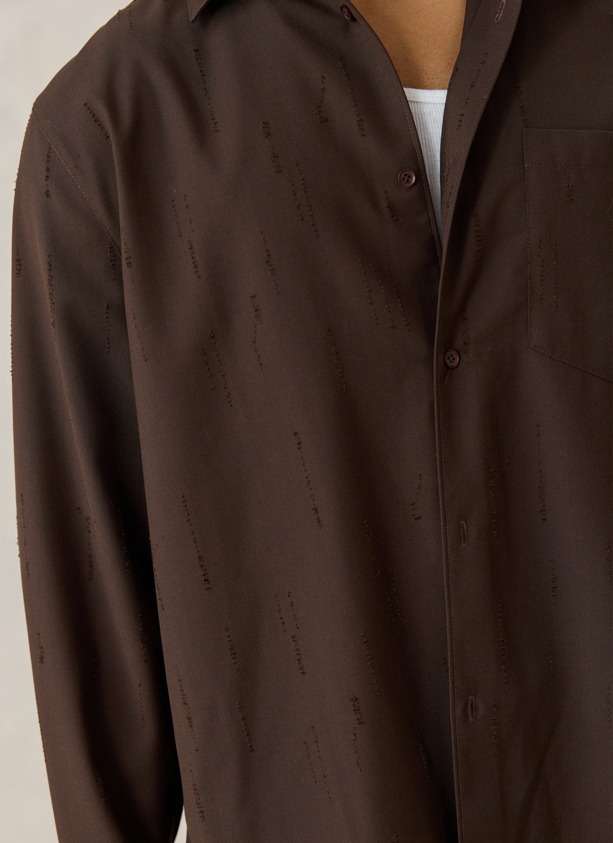 A close-up of the Percival espresso brown Rowley textured jacquard shirt worn open over a white tee.