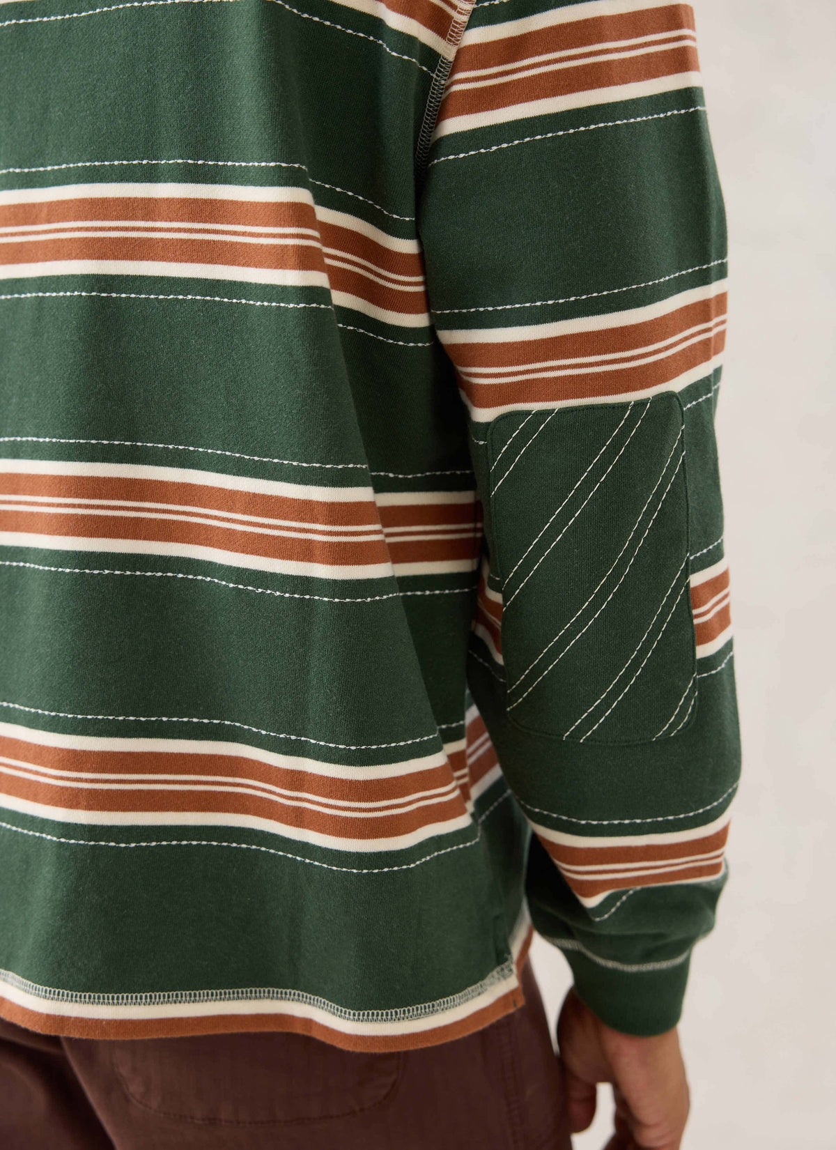 Close-up of the Guinness x Percival striped rugby polo shirt in forest green, showcasing the elbow patch detail.