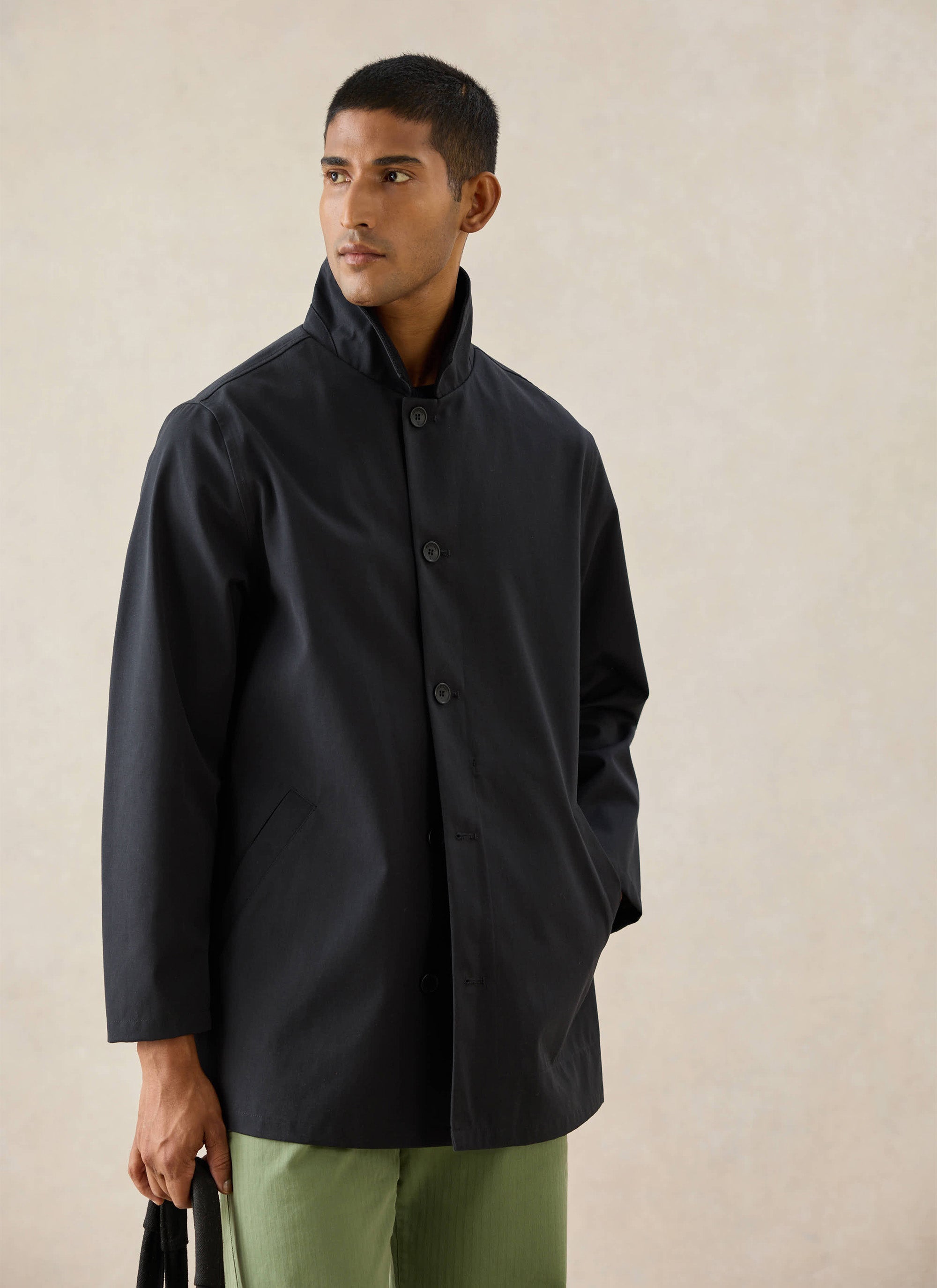 A model wears the black Percival Sherlock Short Trench Coat with a high collar and buttoned front.