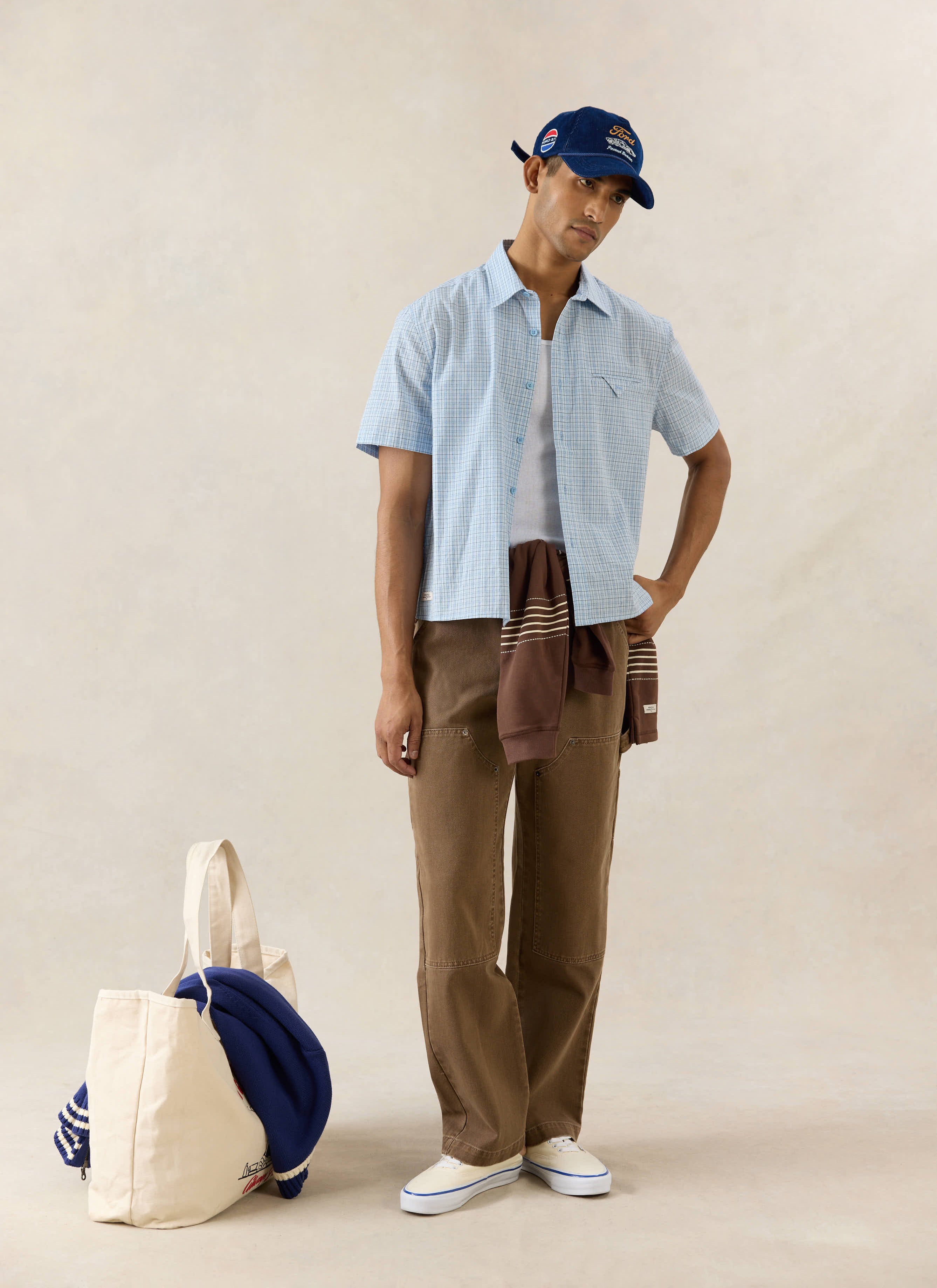 Percival blue check Hinsley boxy cotton shirt, styled with Lucas trousers, an Editor rugby polo, and a blue Spencer cap.