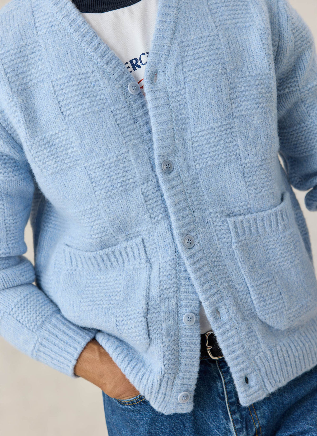 Close-up of Percival light blue alpaca wool knit cardigan, highlighting its textured pattern and front patch pockets.