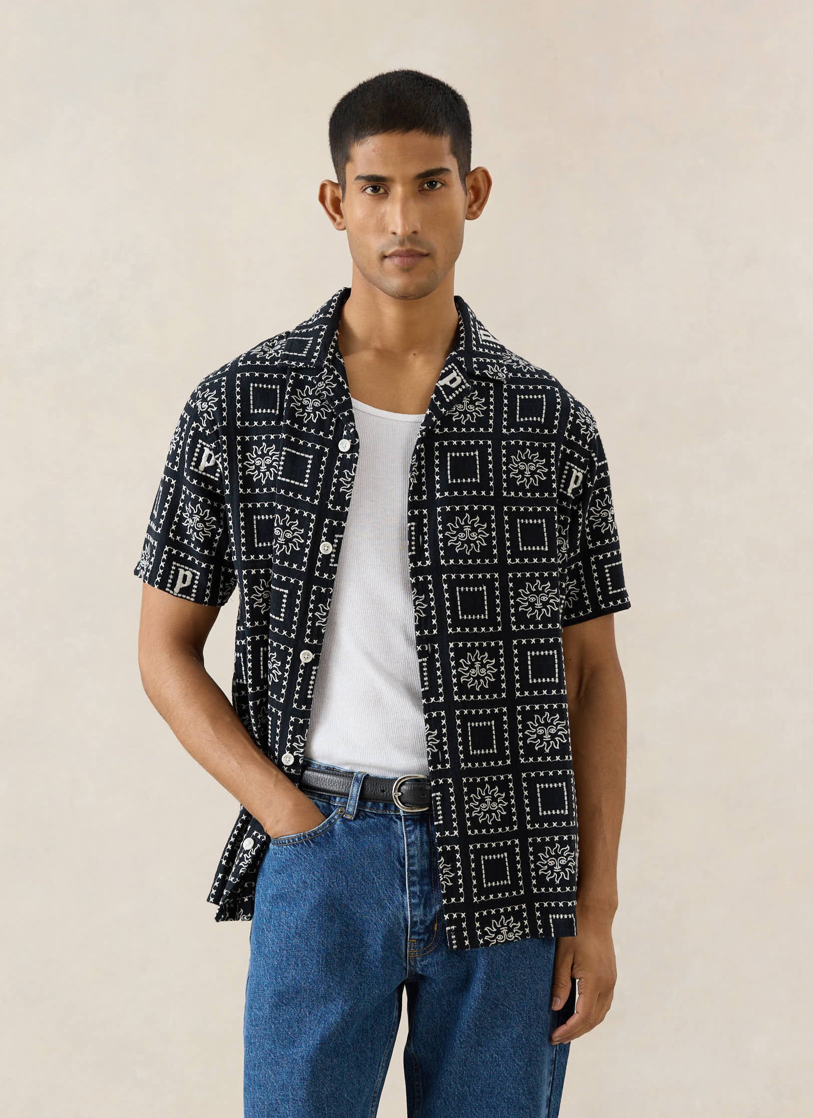 Percival Solis Heaton Cuban shirt in black linen blend, with a white sun print, styled open over a vest and jeans.