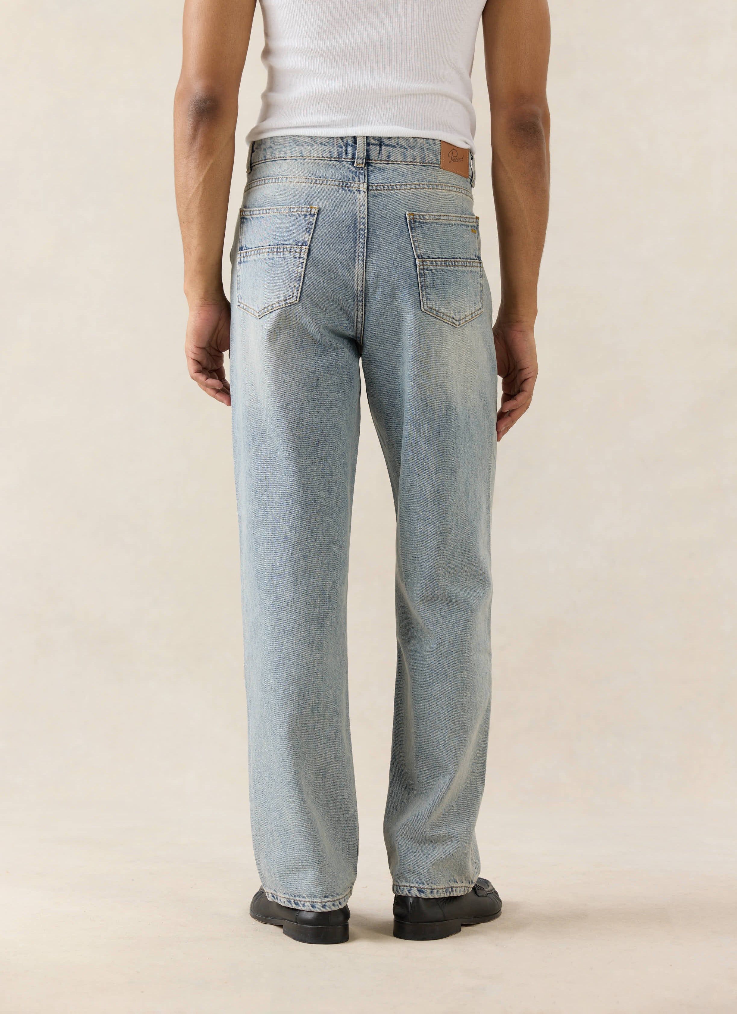 Straight leg Percival jeans in stone wash 12oz cotton denim with a branded leather back patch, seen from behind on a model.