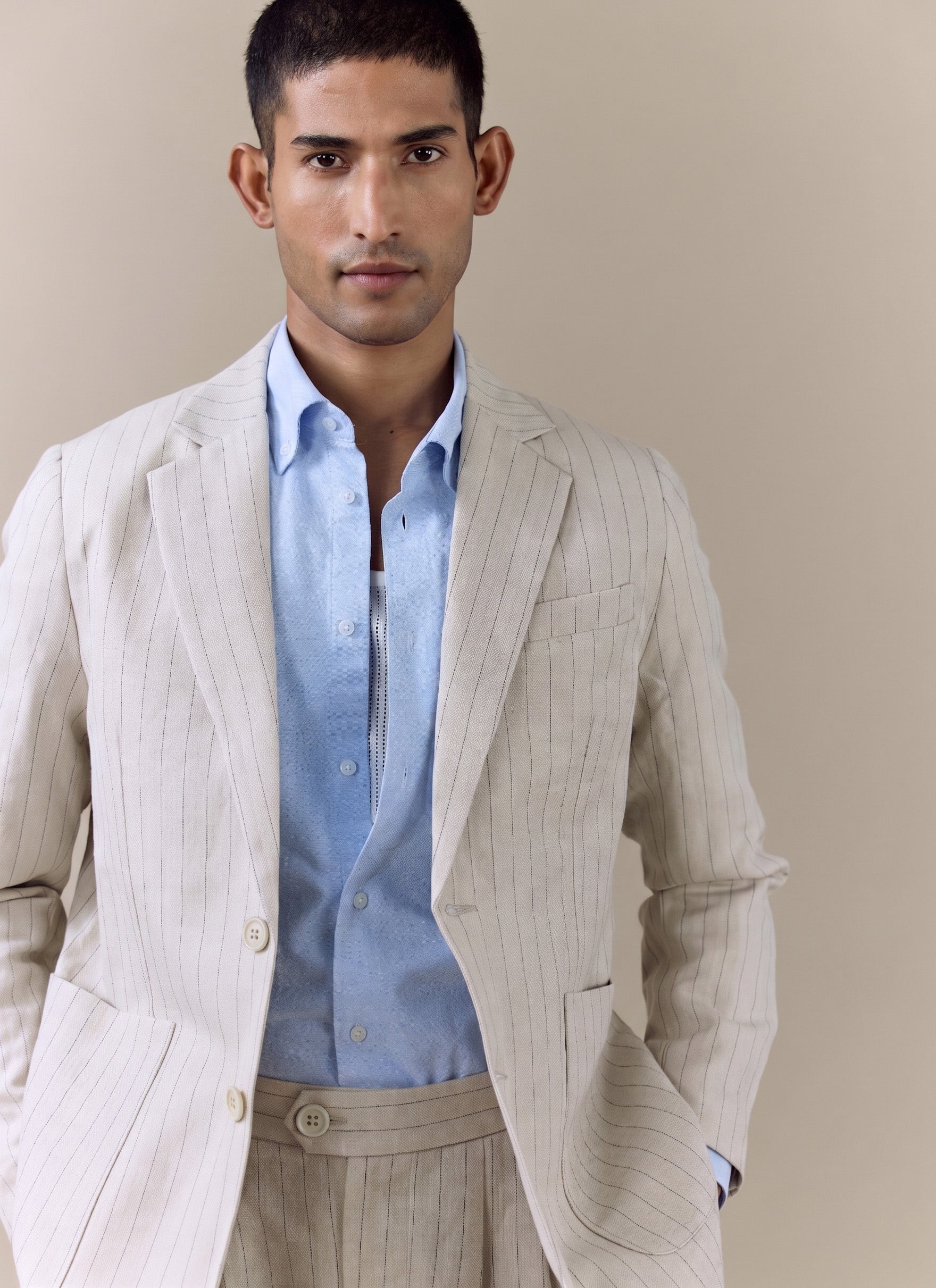 A model wears the Percival striped tailored blazer in cream linen blend over a light blue shirt in a close-up studio shot.
