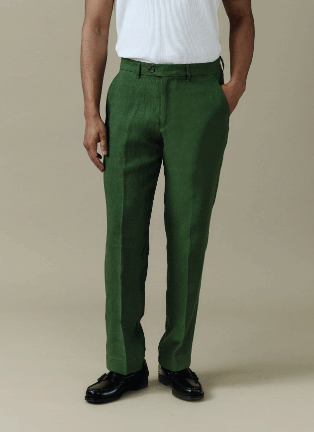 A model wearing the forest green Tailored Linen Trousers by Percival, styled with black loafers.