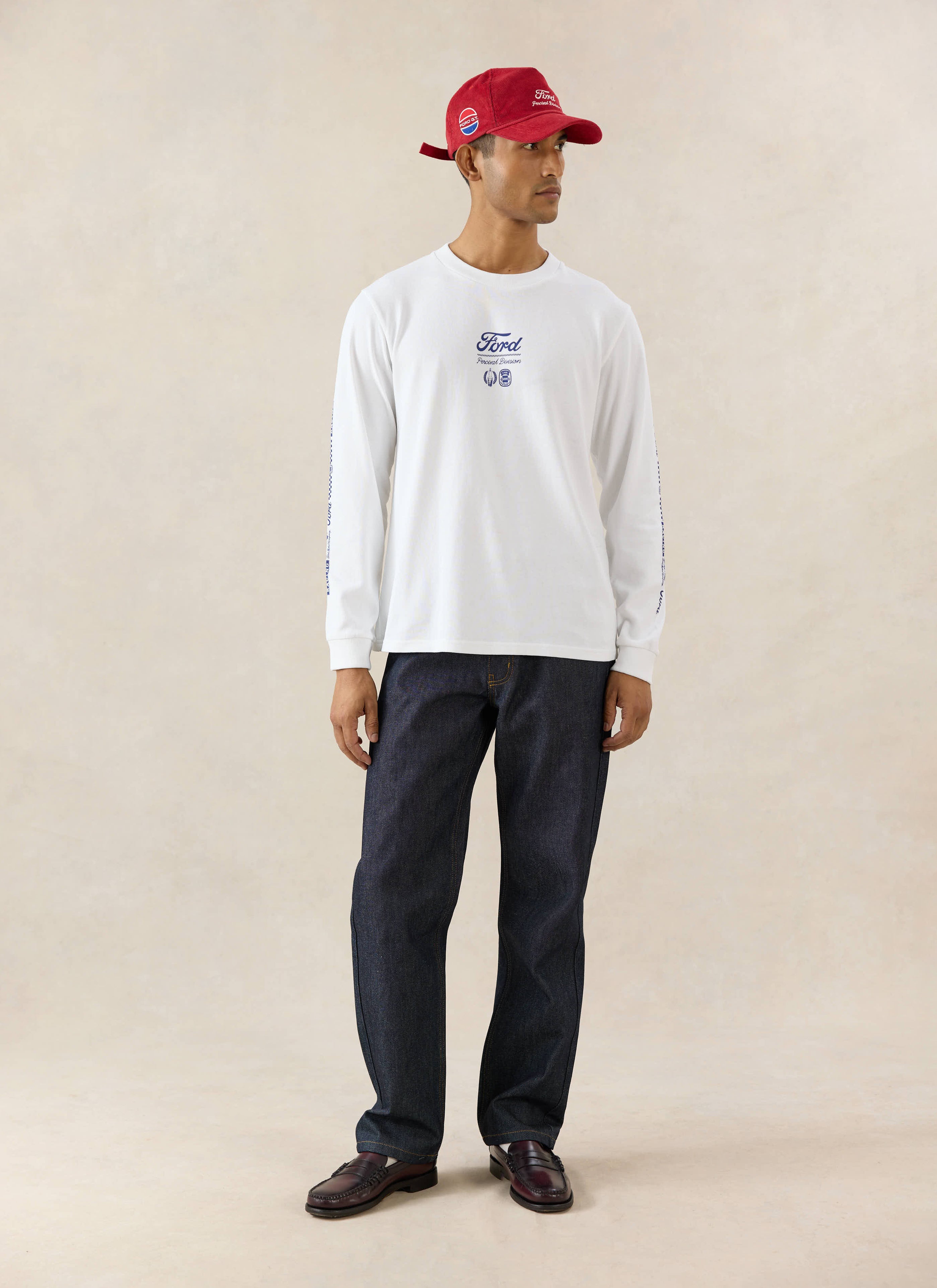 White Ford x Percival Triple Triumph long sleeve t-shirt worn with straight leg heritage denim jeans and a red cap.