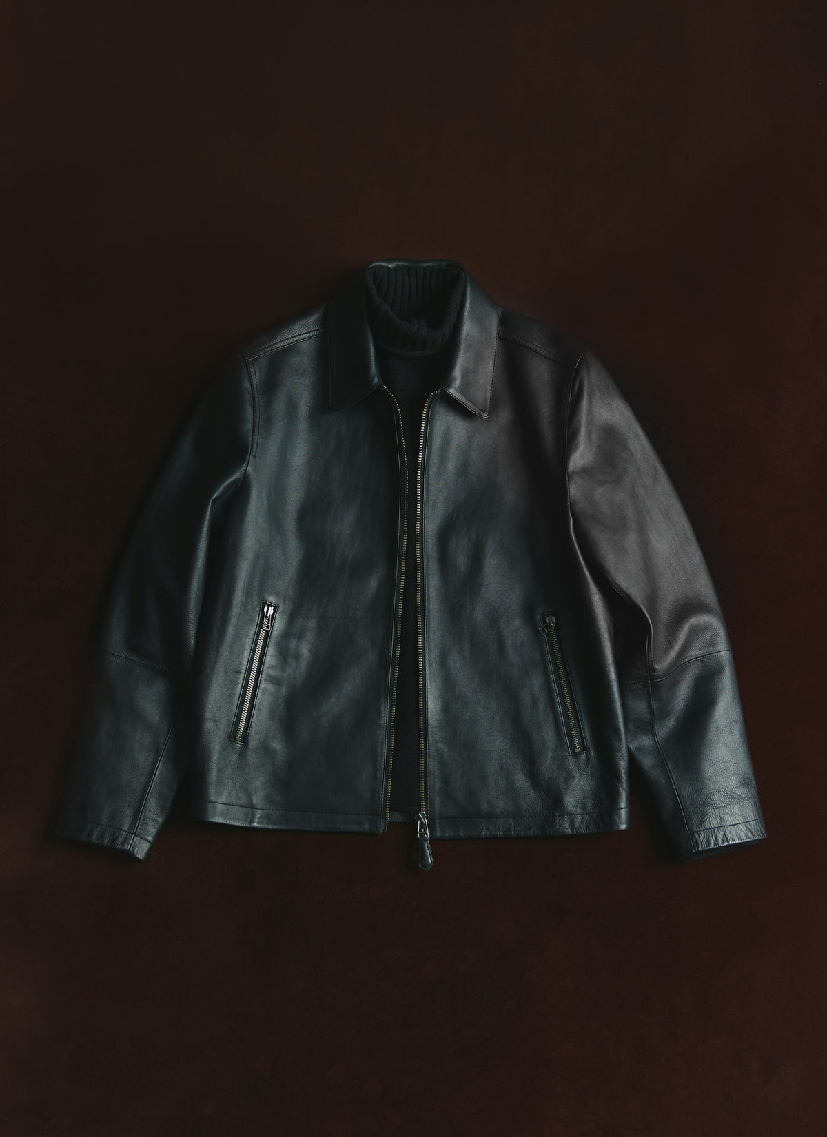 The Percival Turner black leather zip jacket laid flat, showing its 100% leather finish, collar, and zipped side pockets.