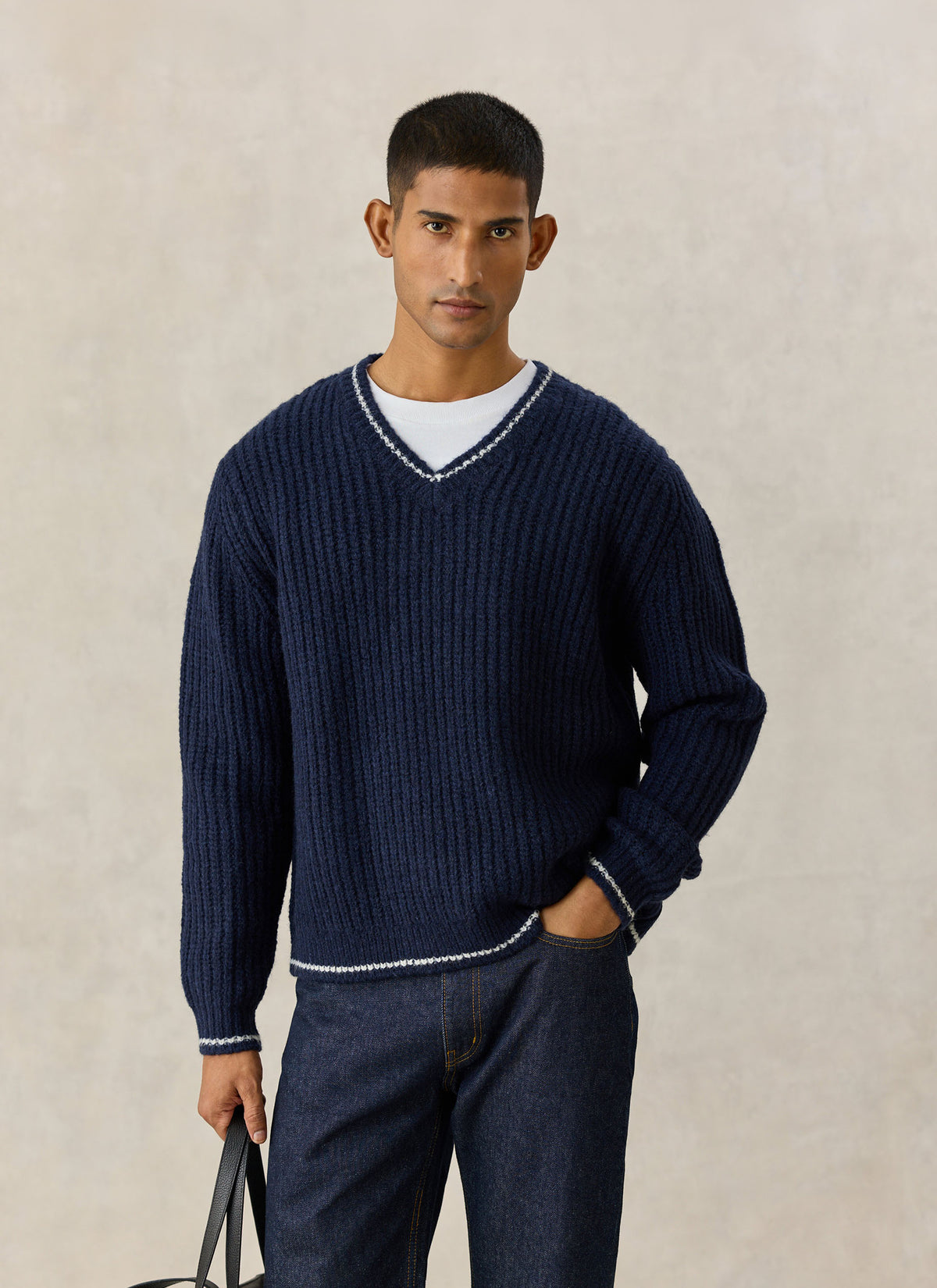 A model wearing the Percival navy V-neck knit jumper in an alpaca wool blend with contrast trim detail.