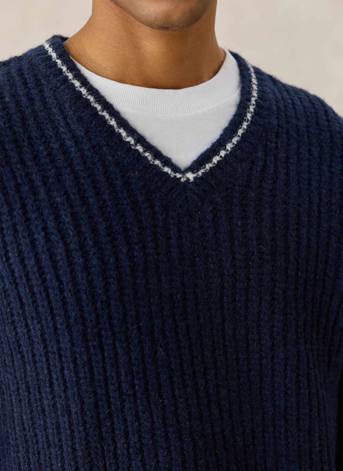 Close-up of the Percival navy V-neck knit jumper showing the textured rib alpaca blend fabric and contrast collar trim.