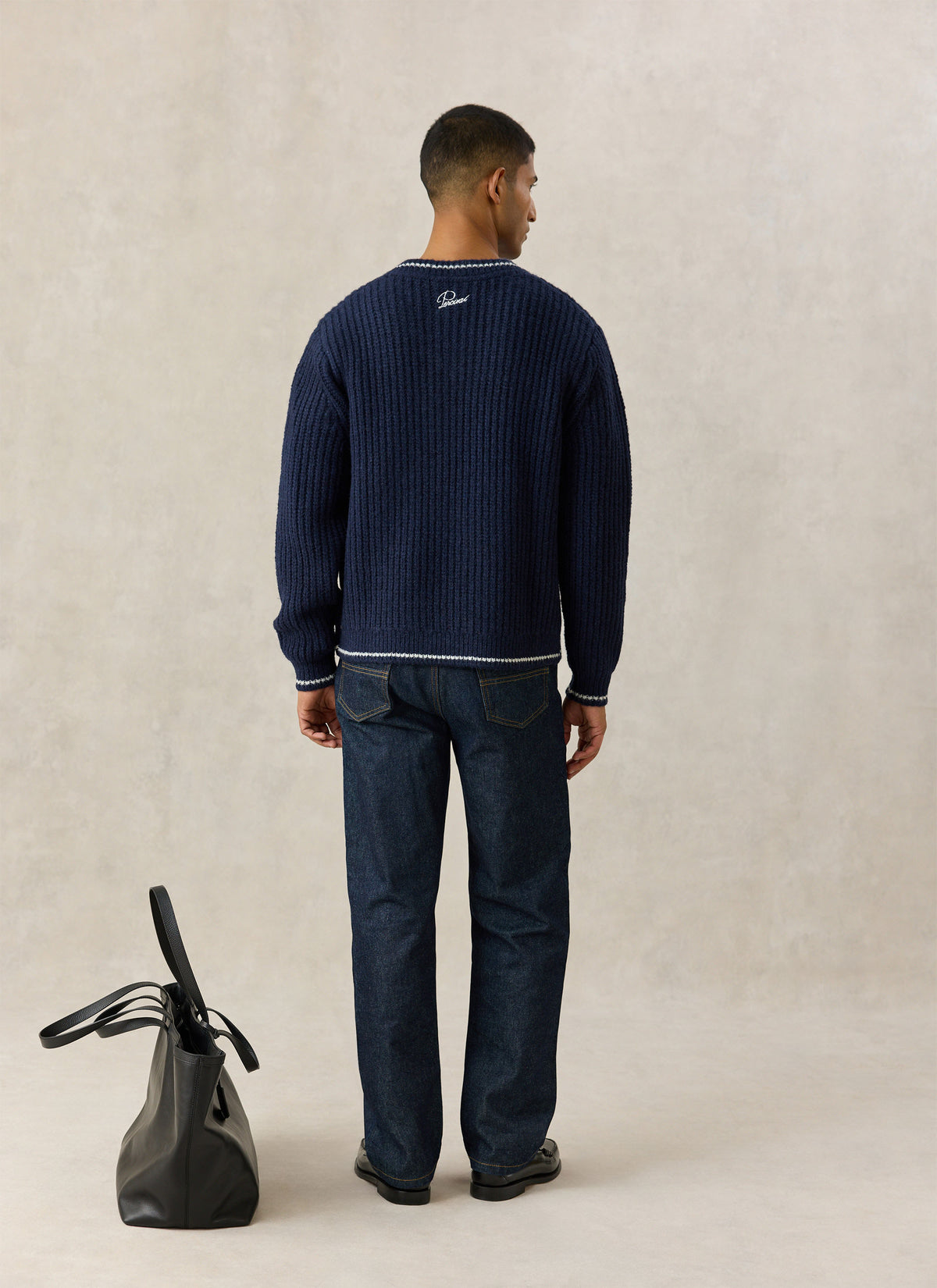 A model from the back wearing the Percival navy V-neck jumper, showing the back neck embroidery.