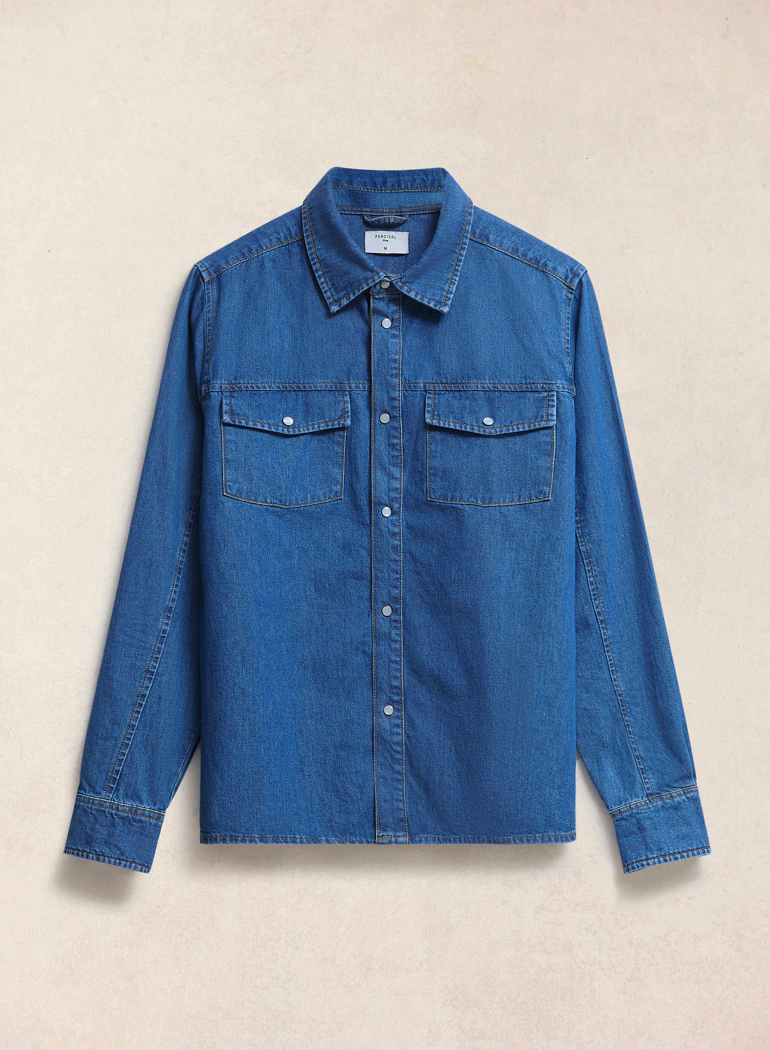 Percival Vintage Wash Western Shirt in mid blue denim, featuring pearl buttons and twin chest pockets, shown flat.