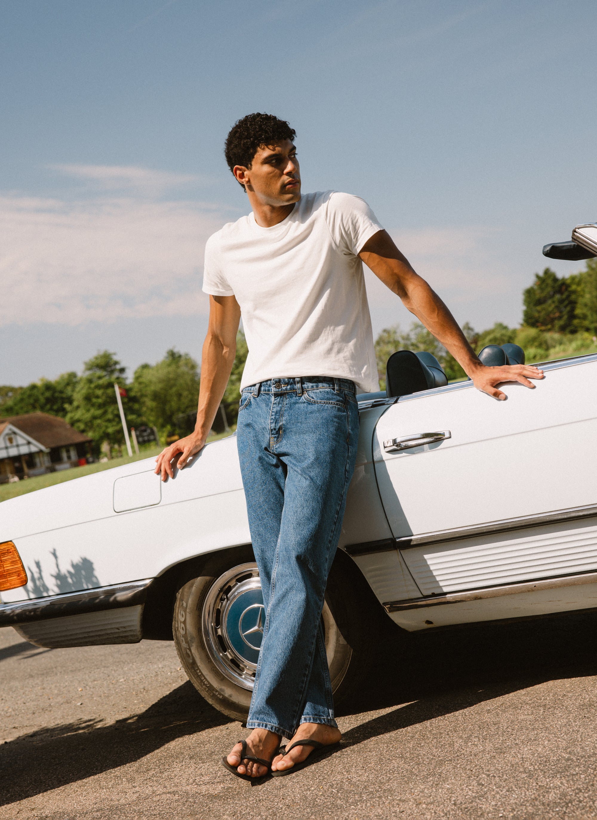 Percival straight leg heritage denim jeans in mid wash blue, worn by a model leaning against a vintage white car.