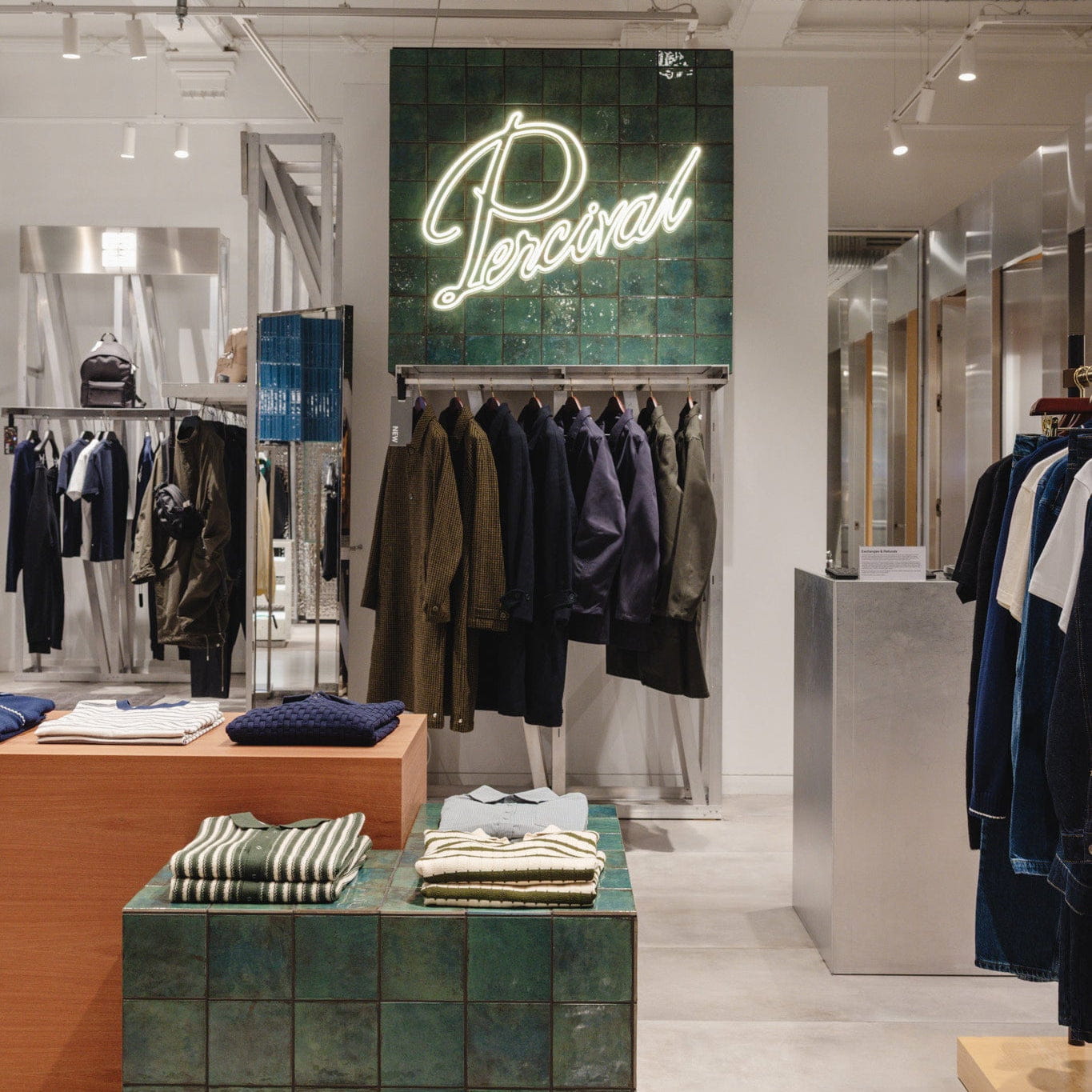 Interior of a clothing store with 'Percival' sign and racks of clothes.