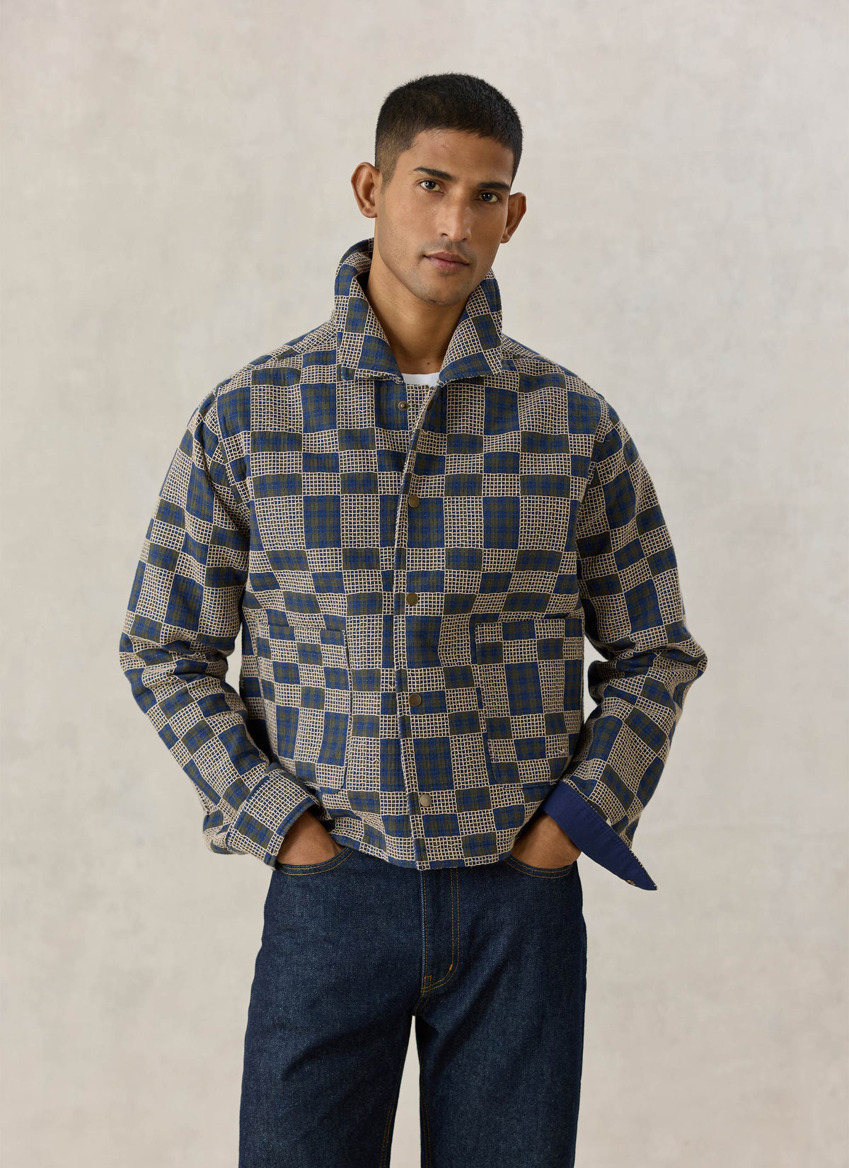 A model wearing the Percival Wallis Grid Check Overshirt in navy cotton, featuring a textured design and popped collar.