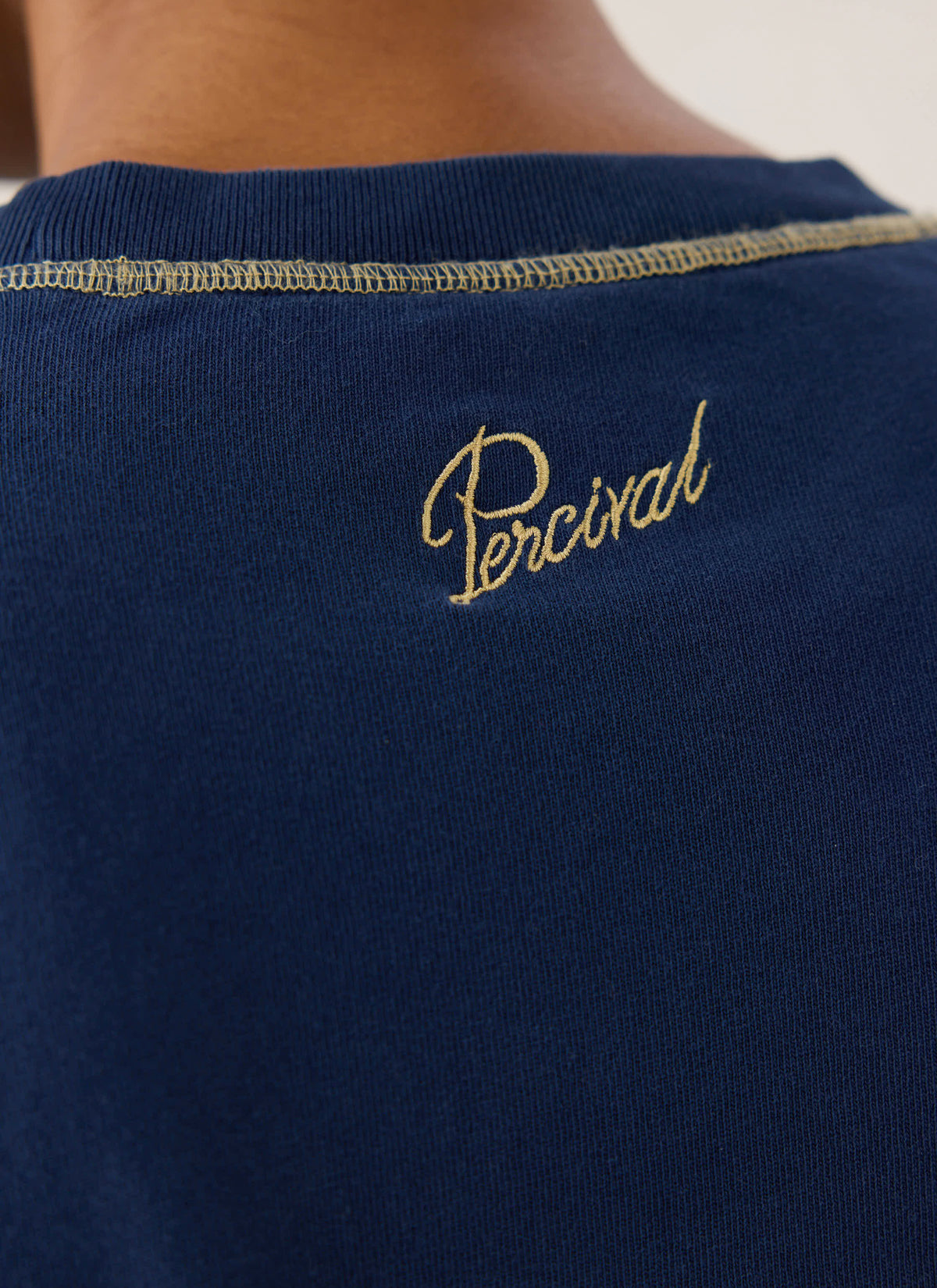 Close-up of the back neck of the navy Guinness x Percival T-shirt, highlighting script embroidery.