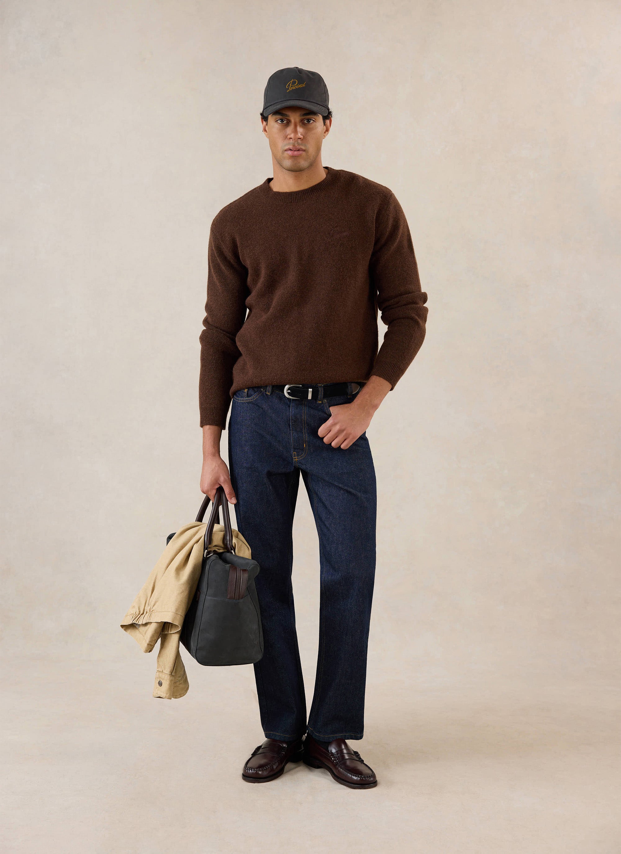 A model wears the espresso Percival mohair boxy crew neck jumper with dark denim jeans, loafers, and a cap.