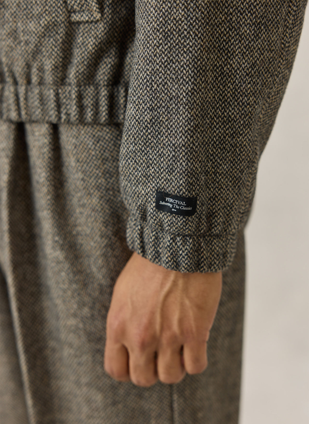 A close-up of the Percival birdseye wool-blend jacket sleeve showing the elasticated cuff and small branded tag.