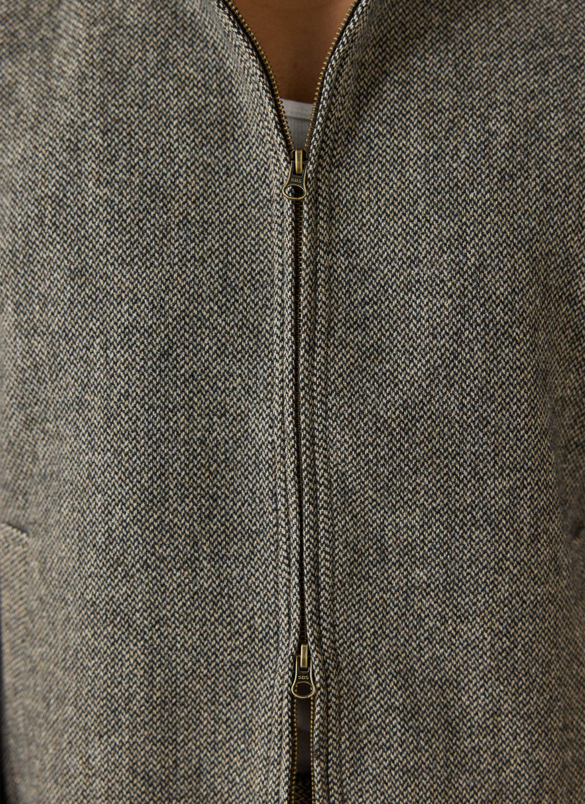 A close-up of the Percival Wilde Harrington jacket in grey birdseye wool blend, showing the two-way front zipper detail.