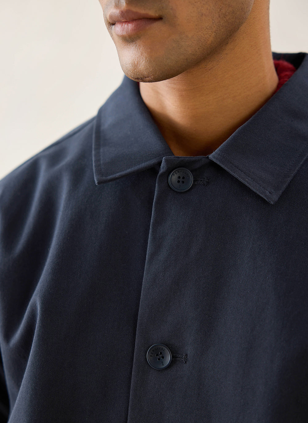 Close-up of a model wearing the midnight Percival Wilson Long Trench Coat, highlighting the collar and button details.