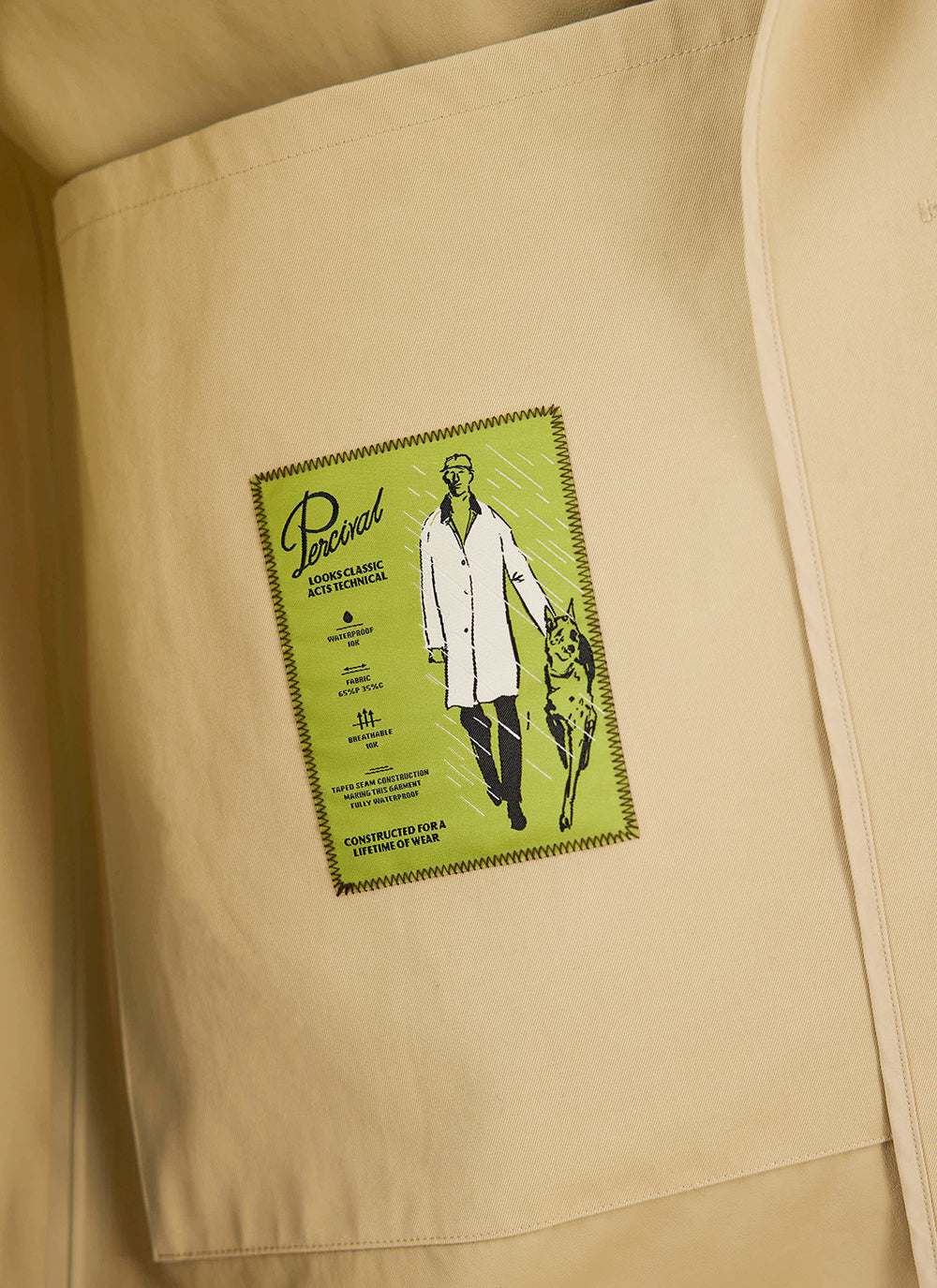 A close-up of the green interior technical label inside the tan Wilson trench coat by Percival.