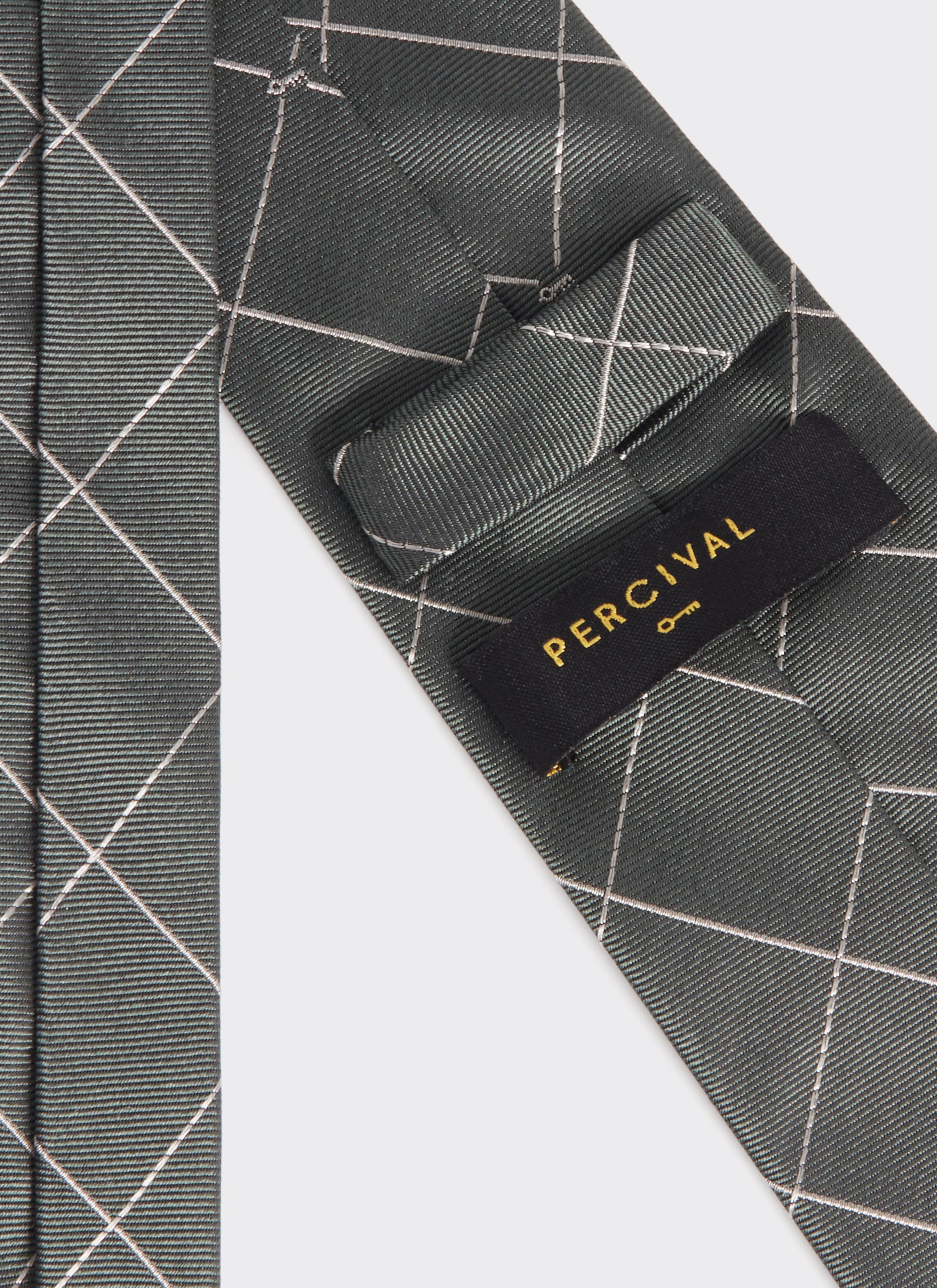 Close-up of the forest green silk Window Pane Key Jacquard Tie by Percival, showing the brand label and grid pattern.