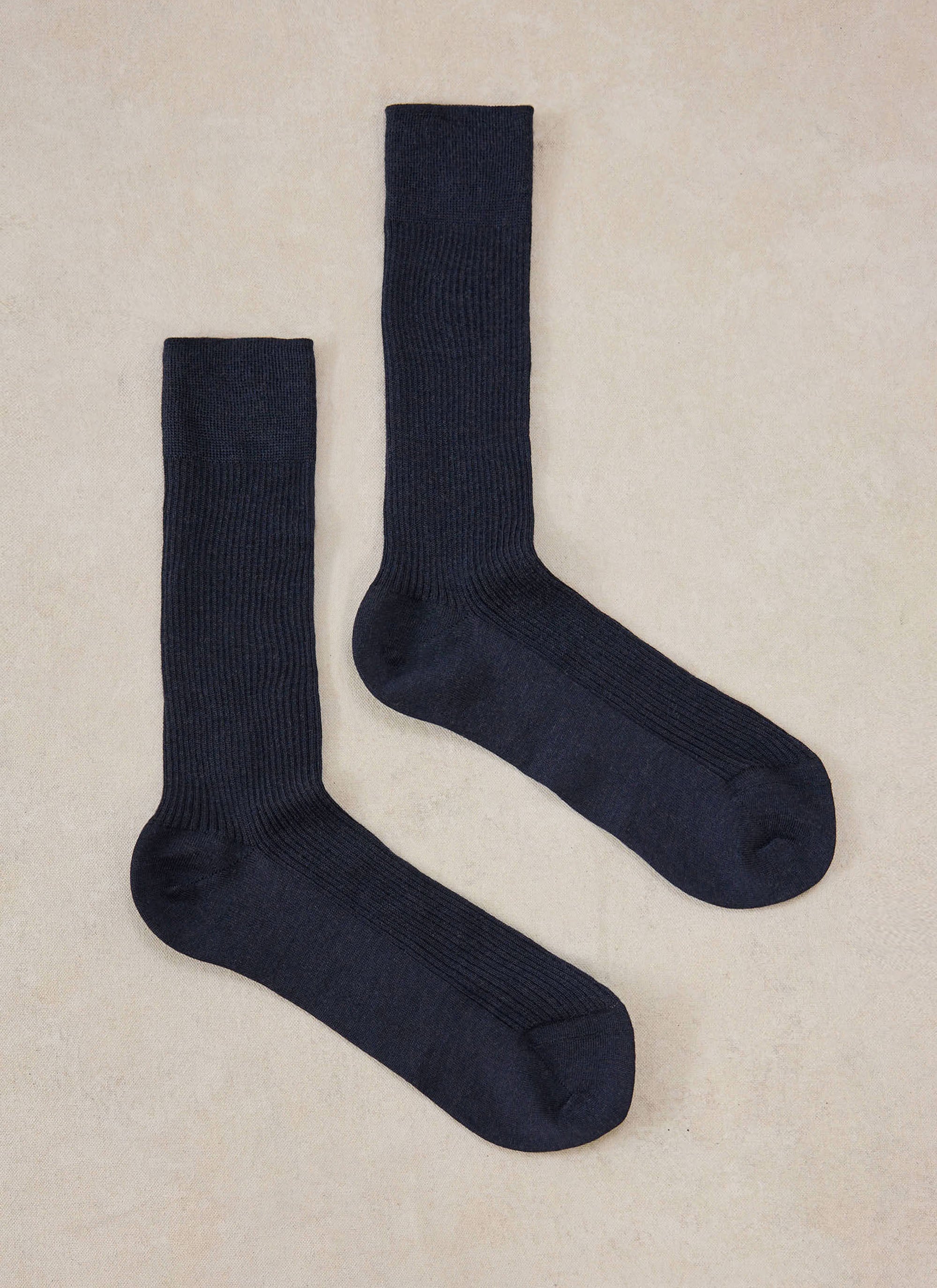 A pair of navy merino wool socks from Percival laid flat on a neutral background.