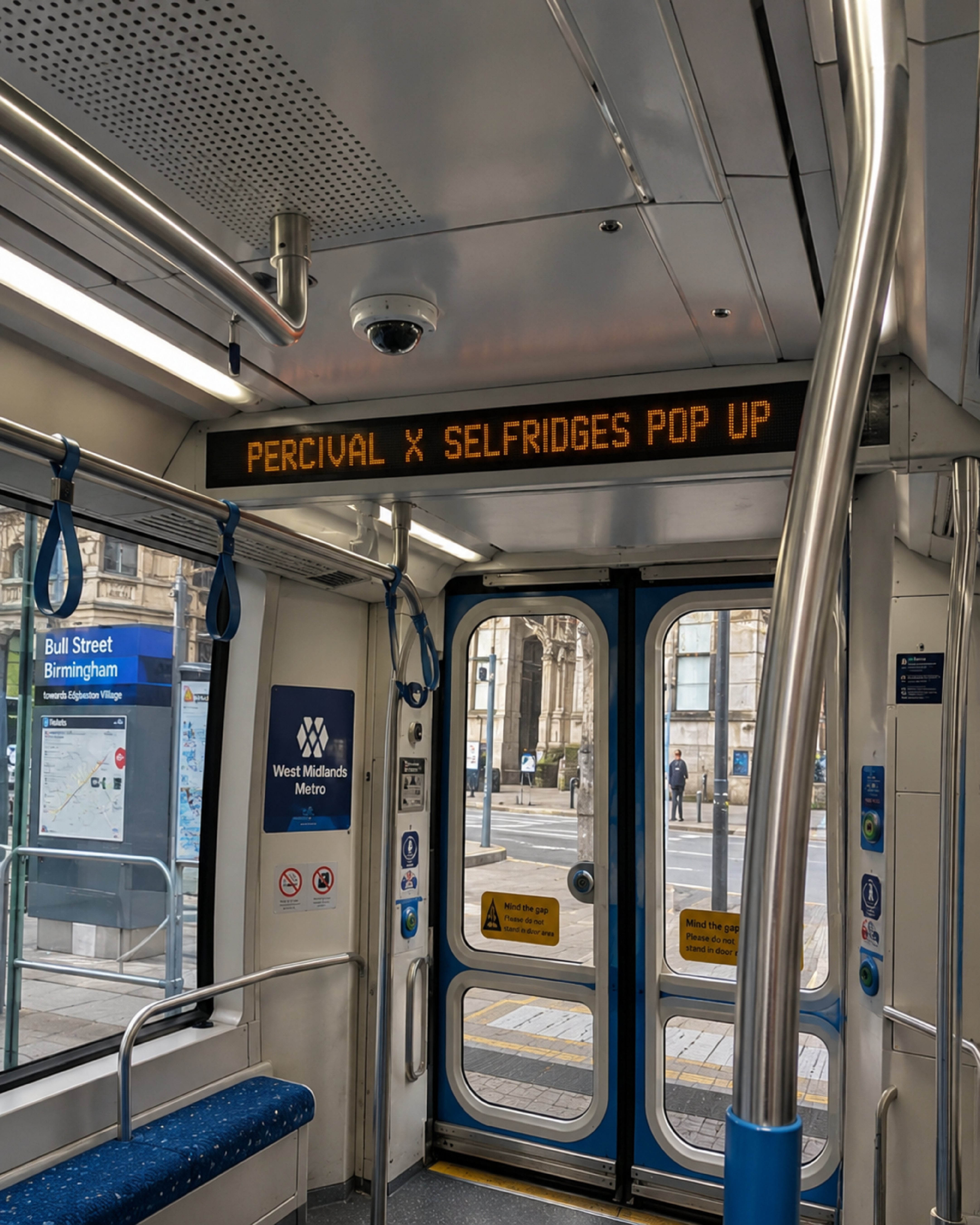 Interior view of a train with open doors and a digital display sign showing the route to the Percival x Selfridges pop-up store at Birmingham New Street station.