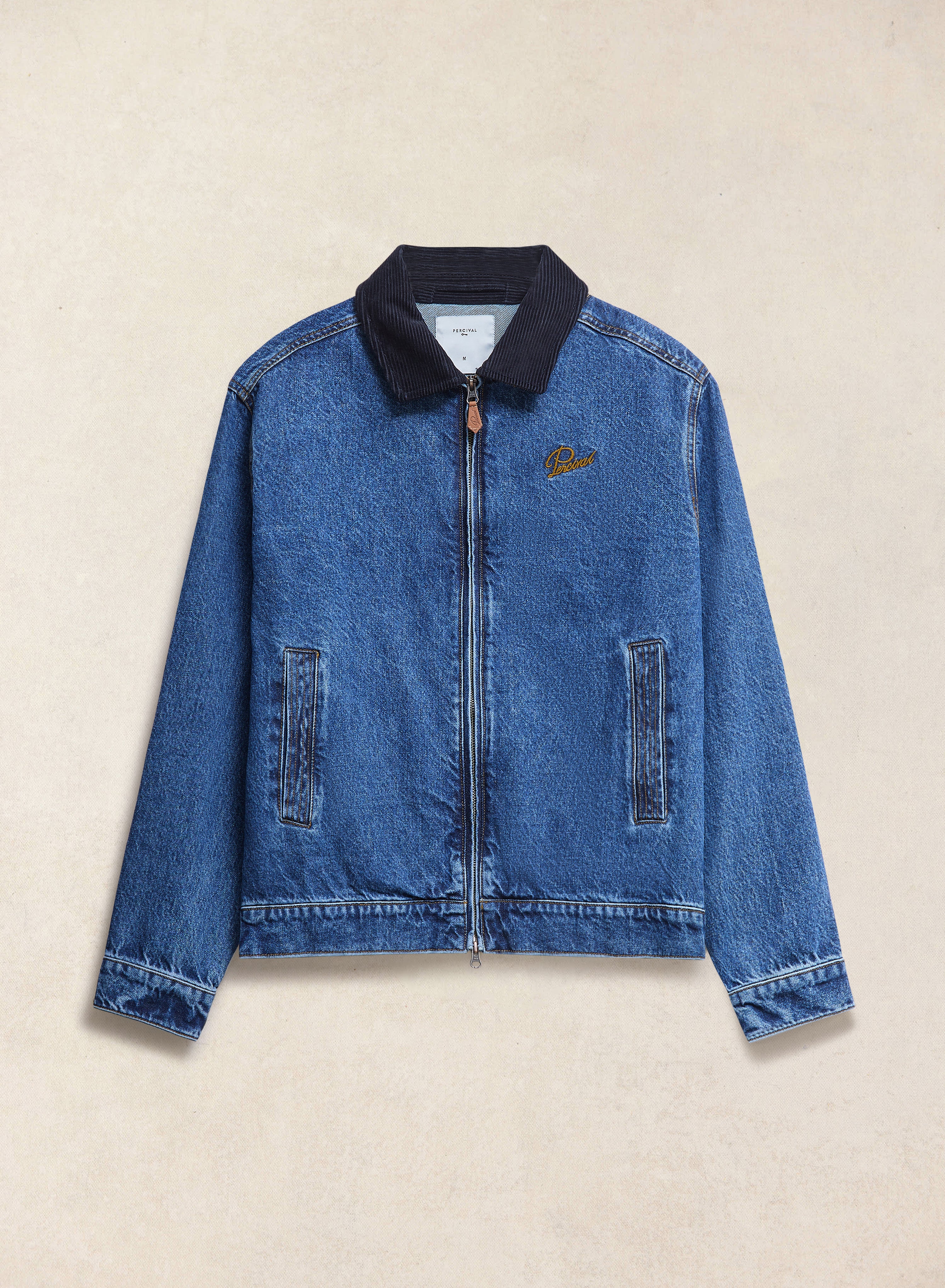 Mid wash blue Percival Mackey zip denim jacket featuring a contrasting dark cord collar, zip pockets and chest embroidery.