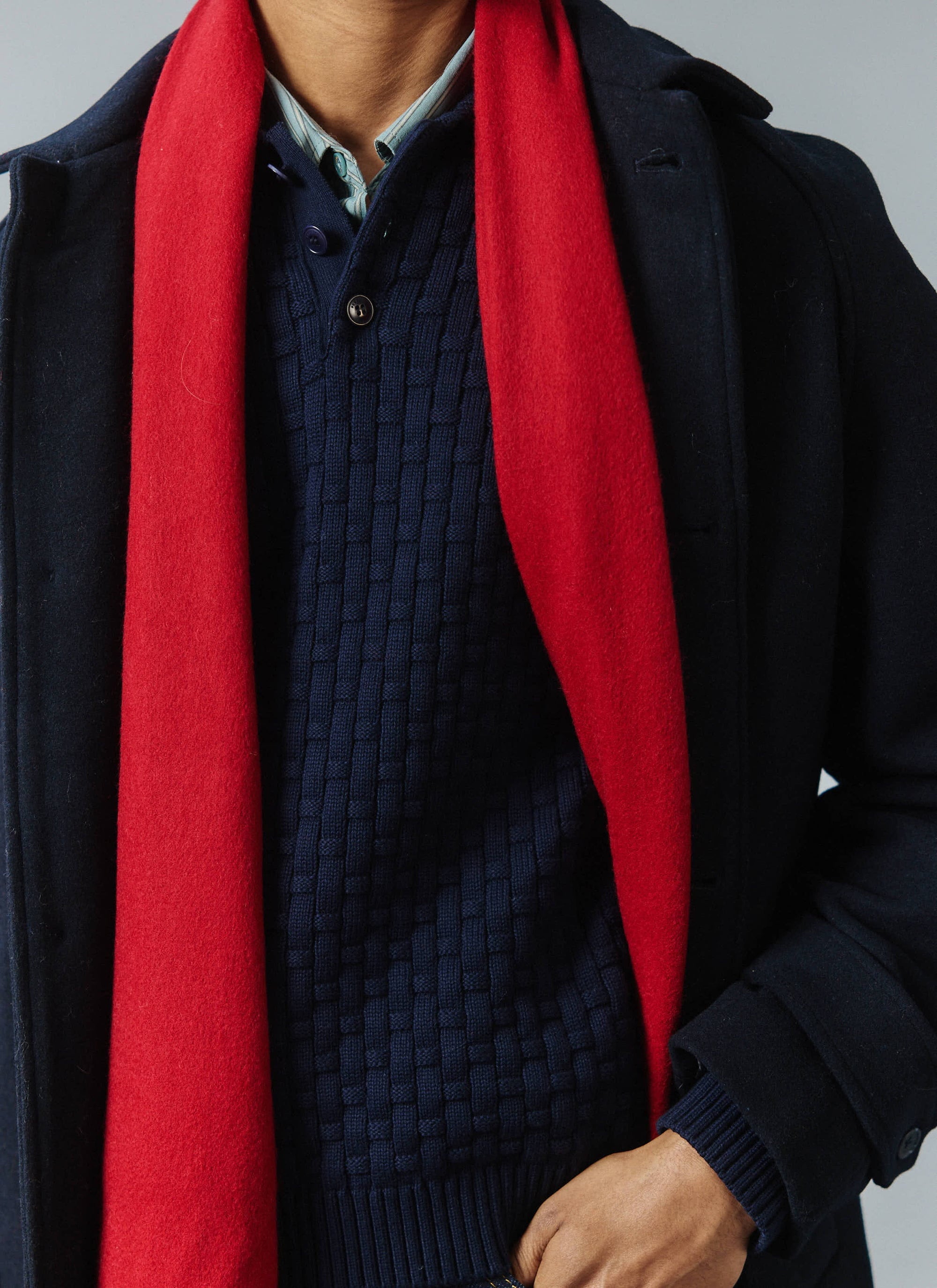 A close-up of a model wearing the Percival navy wool car coat layered with the vibrant red Tolkein scarf.