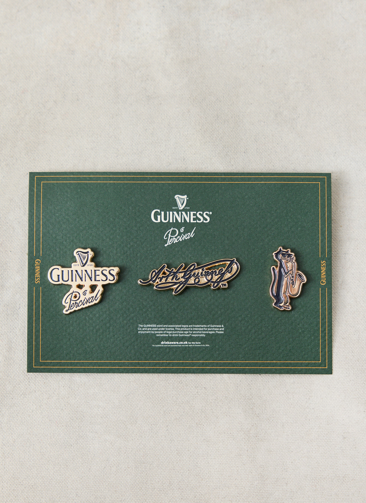 The Guinness x Percival 3 Pack Pins displayed on a green presentation card, featuring gold-tone metallic enamel pin badges.