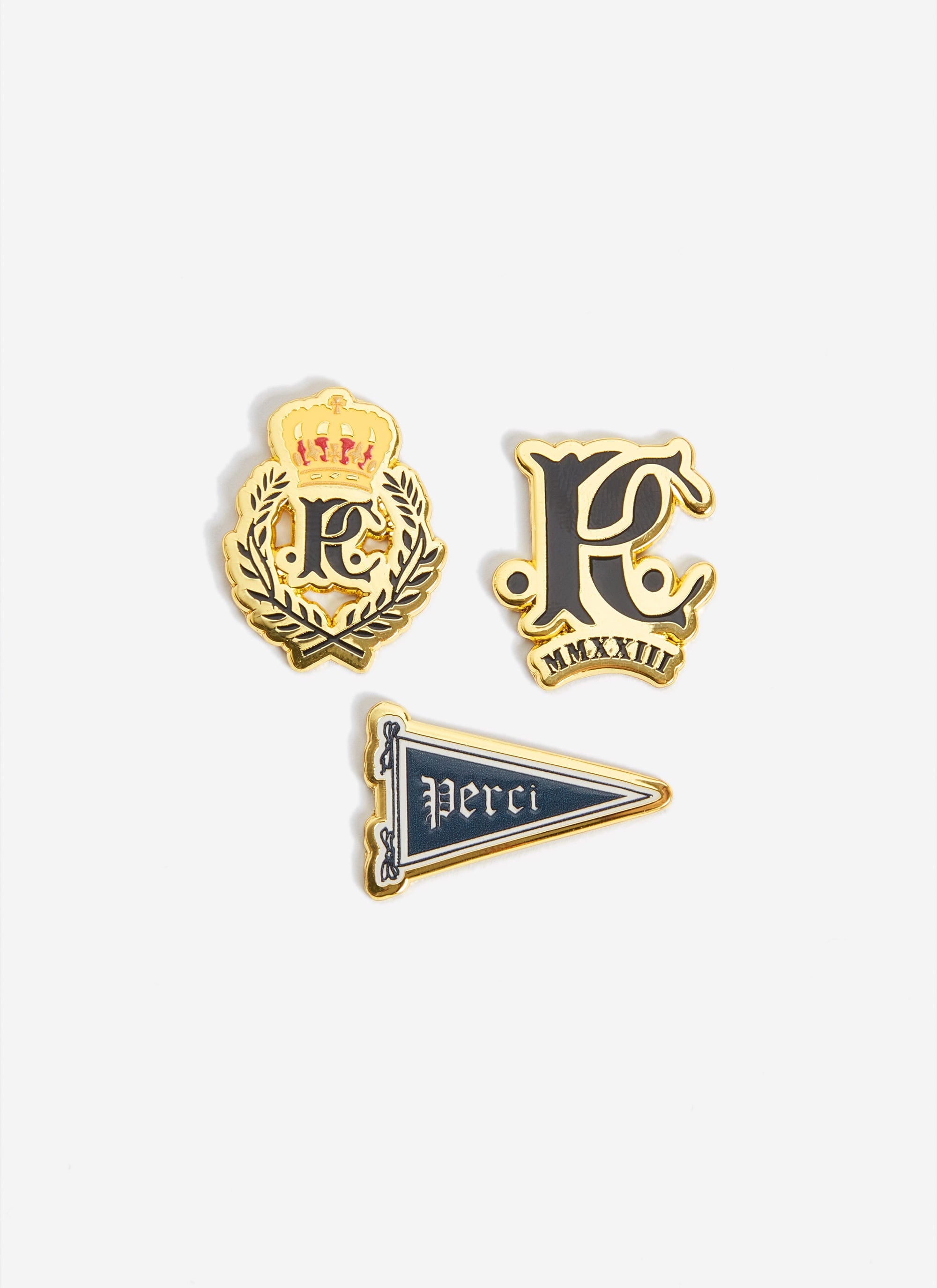 The three gold and black enamel pin badges from the Champion x Percival collaboration, shot against a plain white background.