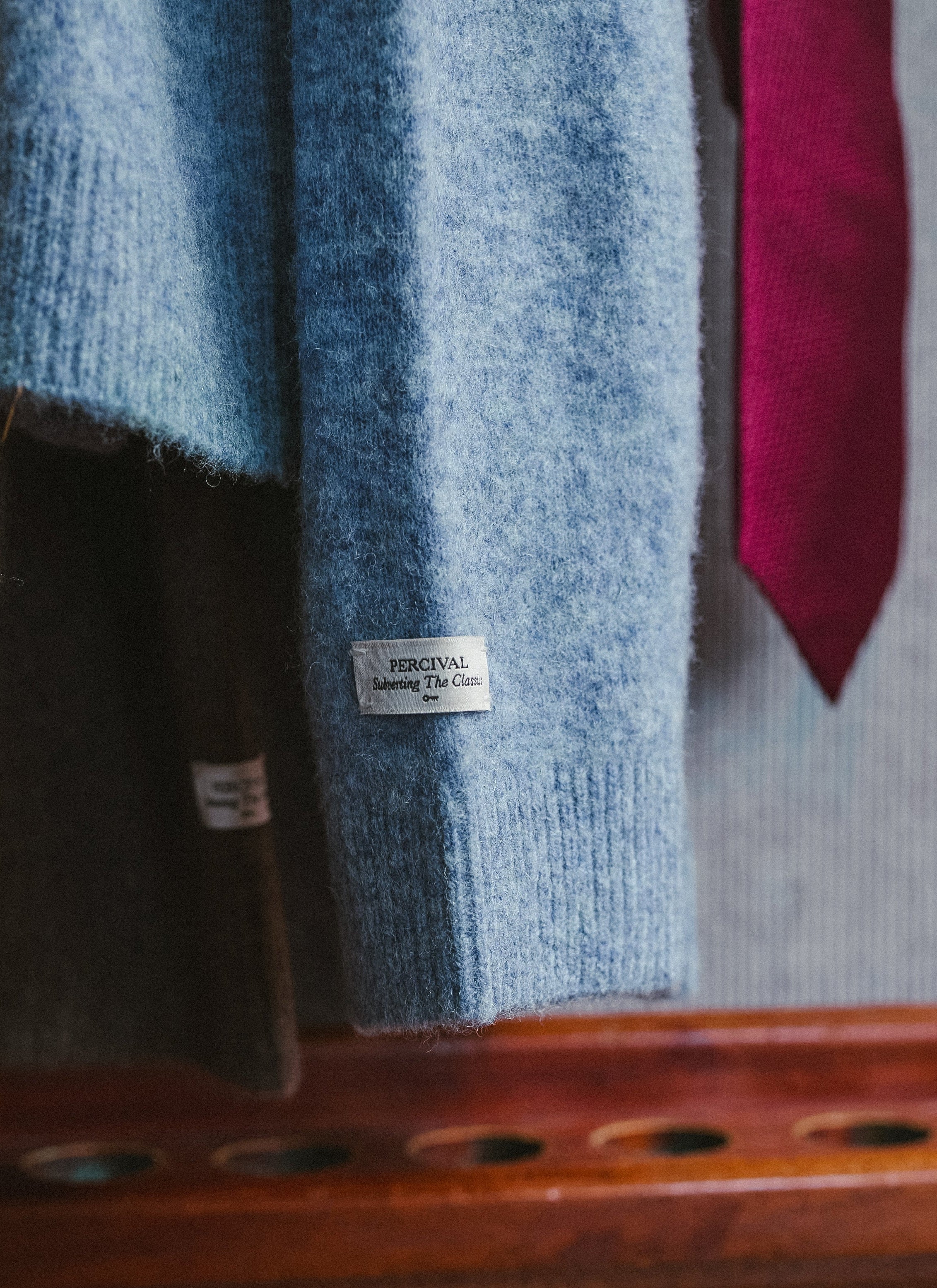 A close-up of the branded sleeve tab on the heather blue Percival yak wool collared cardigan.