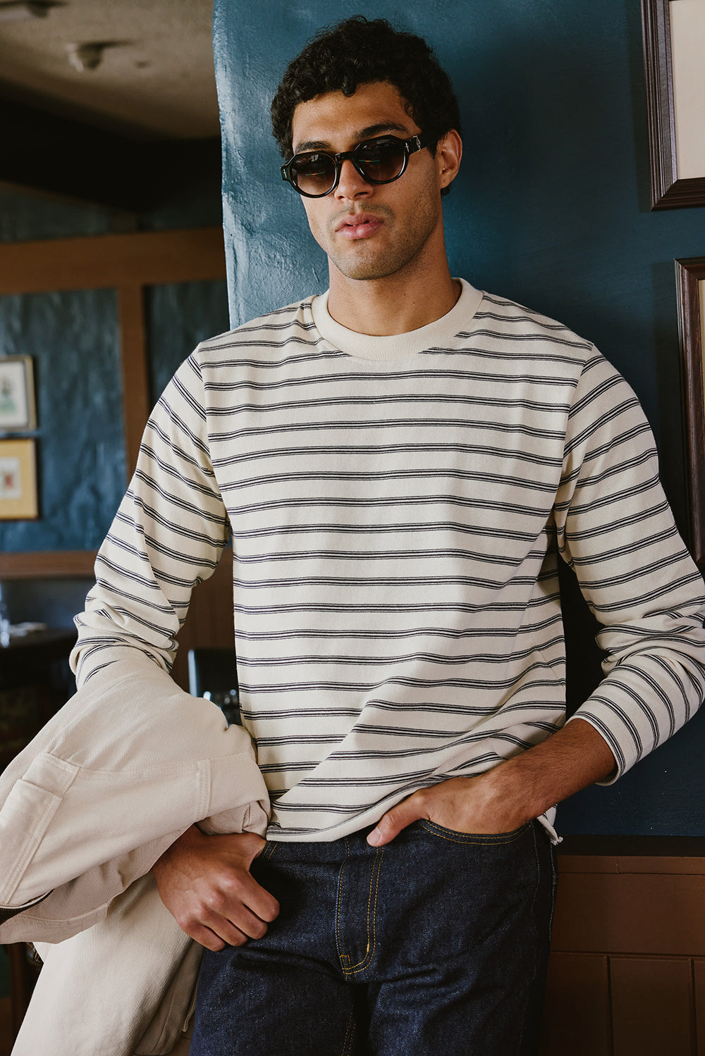 A model wears the white stripe Percival Arlo long sleeve Breton T-shirt, styled with sunglasses and dark jeans.