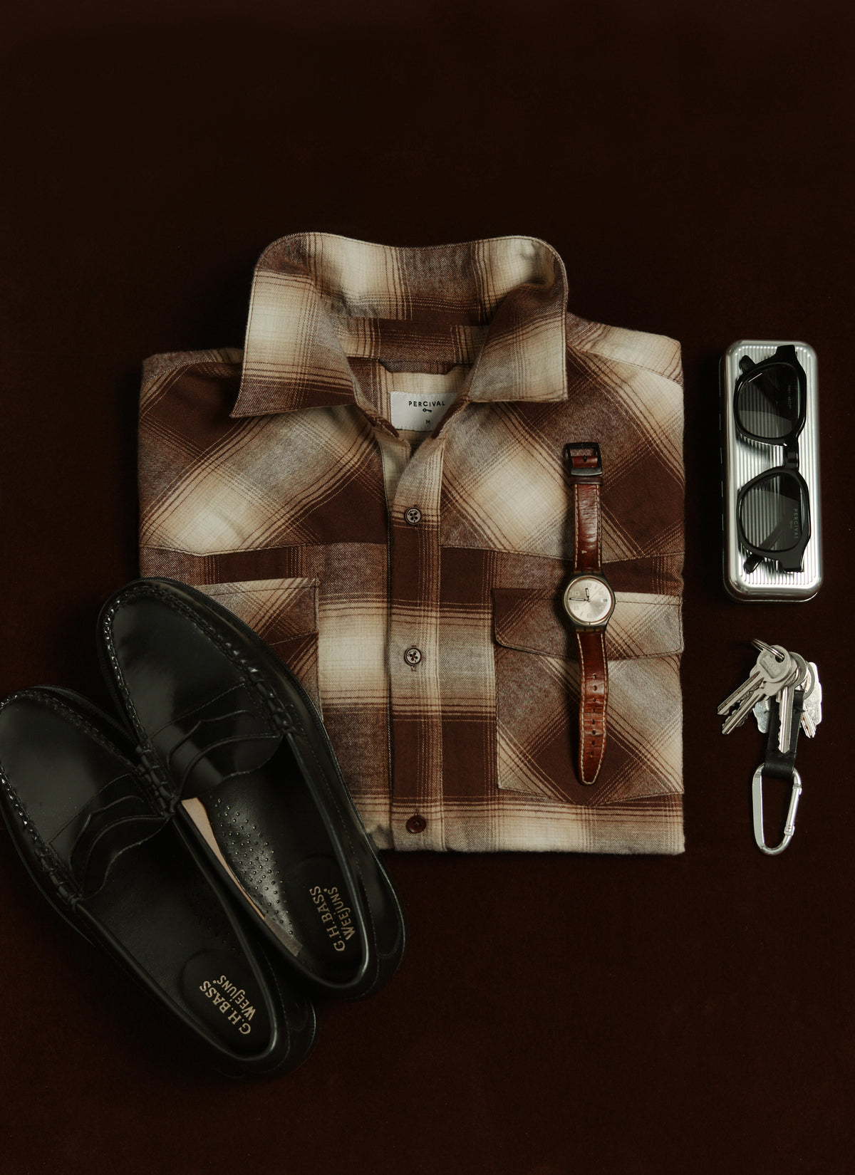 Flat lay of the Percival brown checked cotton western shirt paired with black loafers, a wristwatch, sunglasses, and keys.