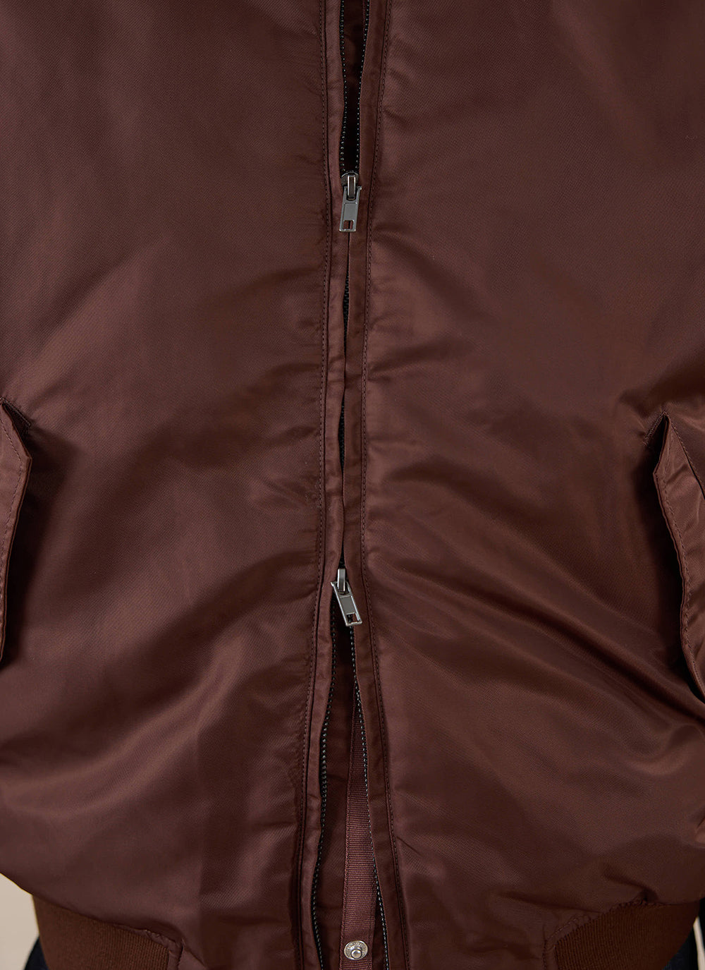 Close-up of the espresso brown Percival nylon bomber jacket showing the front two-way zip and pockets.