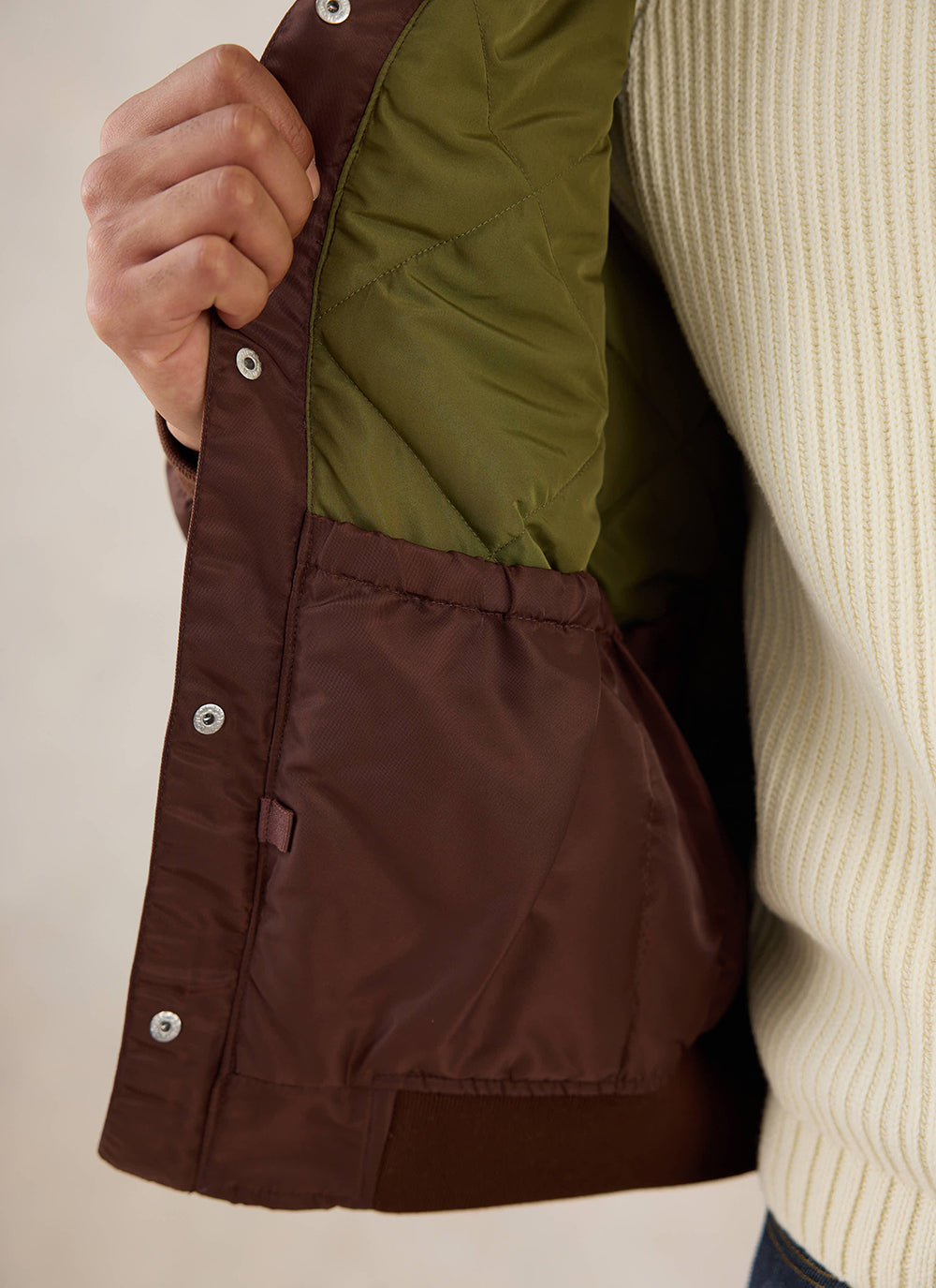 A close-up of the interior lining and pocket of the espresso nylon bomber jacket from Percival.