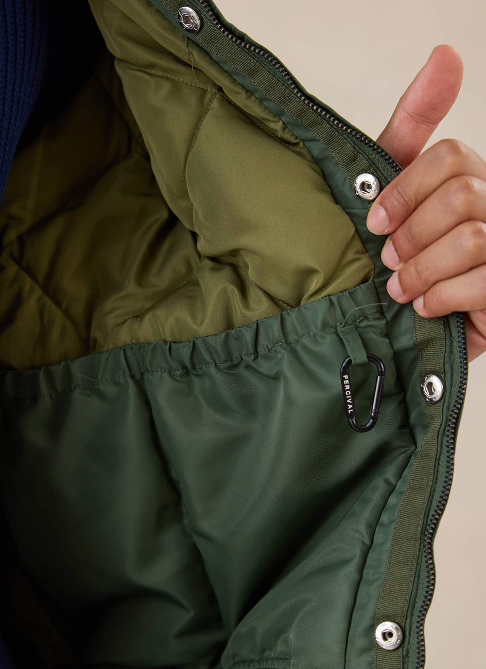 A close-up of the interior lining and pocket of the forest nylon bomber jacket from Percival.