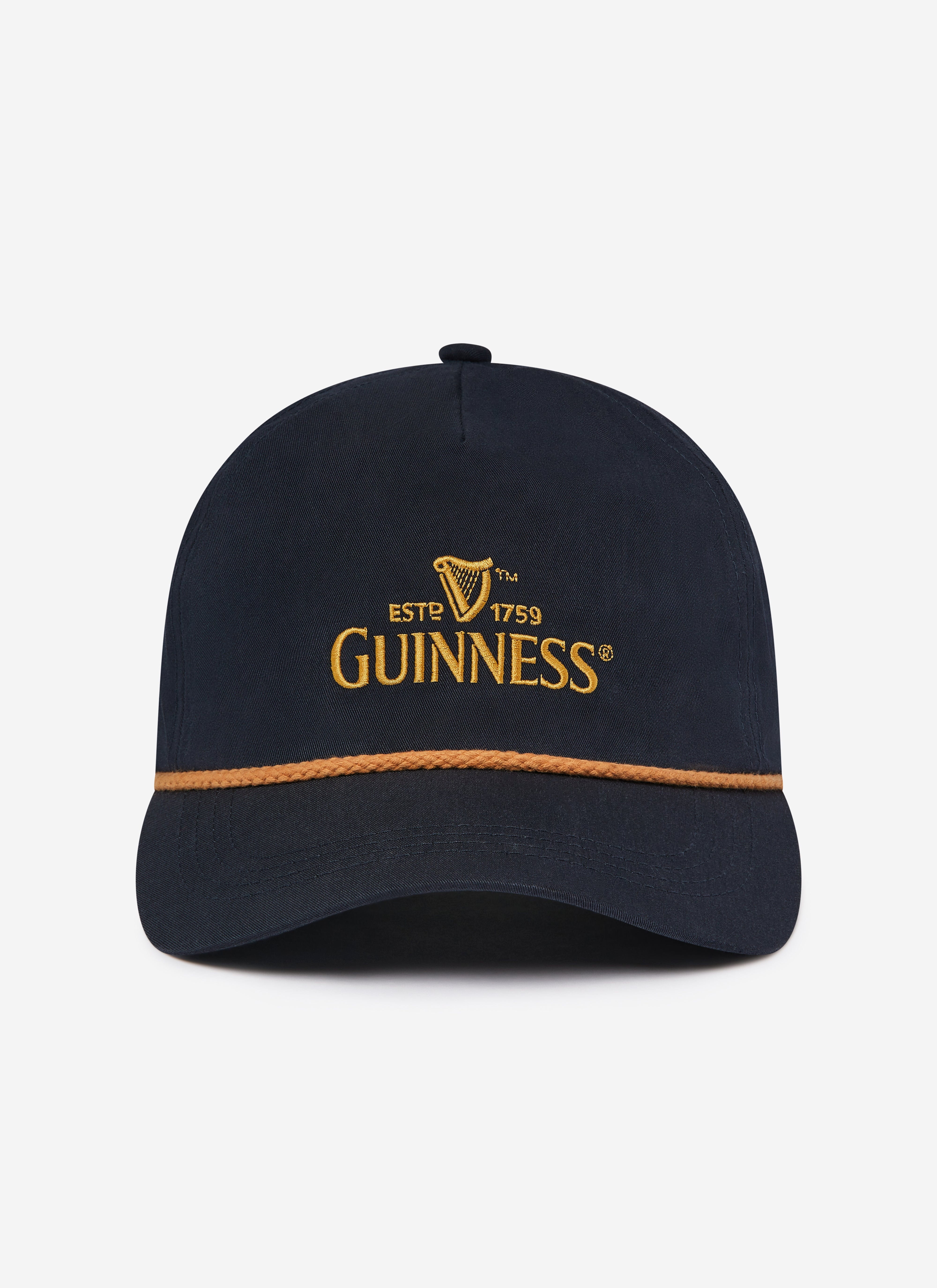A front view of the navy Guinness x Percival collaboration cap, with its iconic gold embroidered logo and rope detail.