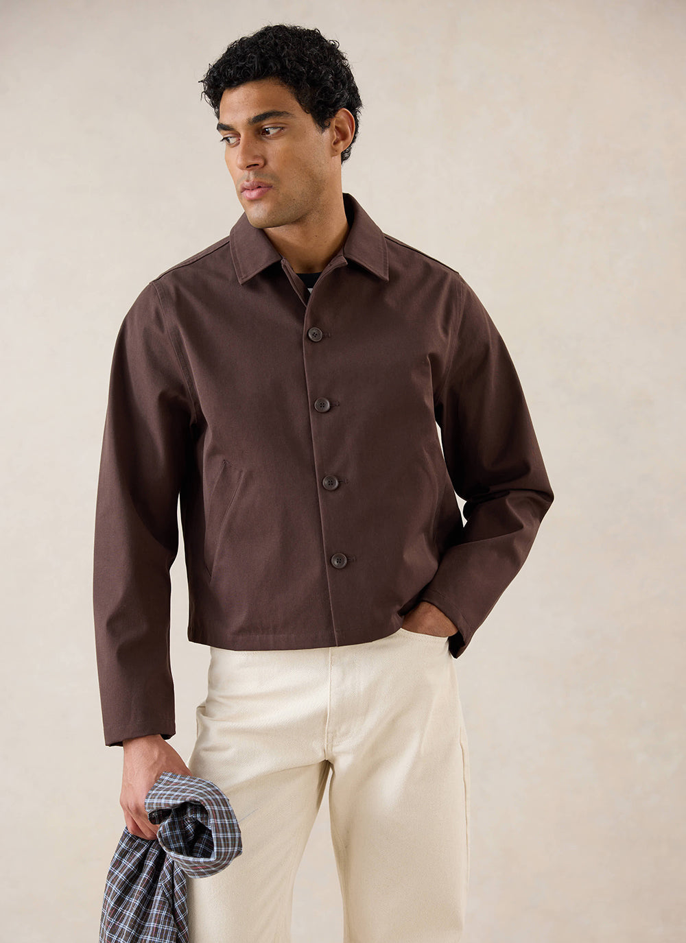 A model wears the espresso Percival Carter Cropped Trench Coat with cream trousers in a studio shot.