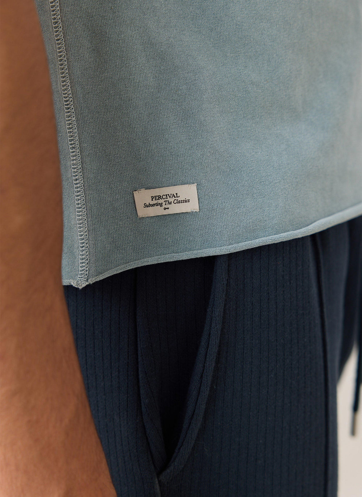 A close-up of the light blue Percival Casey vintage wash cropped t-shirt showing the hem tag and organic cotton texture.