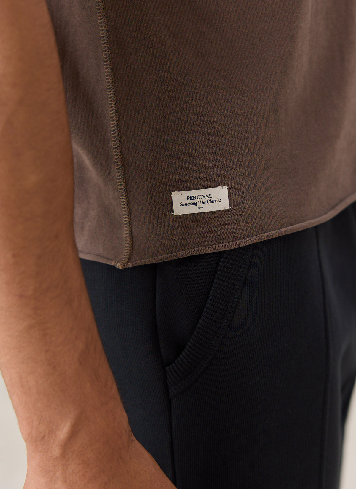 A close-up of the brown Percival Casey cropped T-shirt showing the overdyed label near the hem.